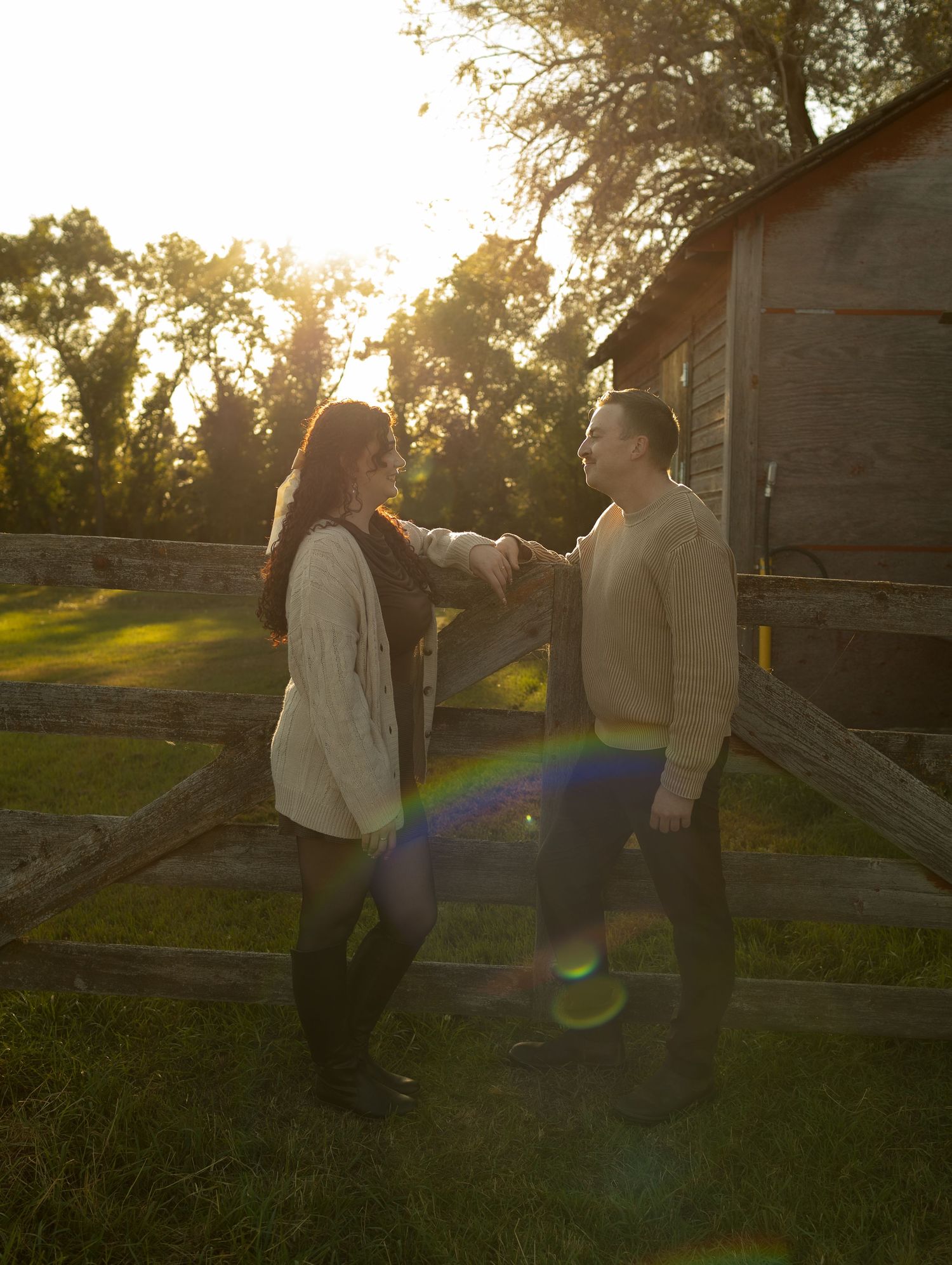 A couple shares an intimate moment in a garden setting during sunset with lens flare effects.