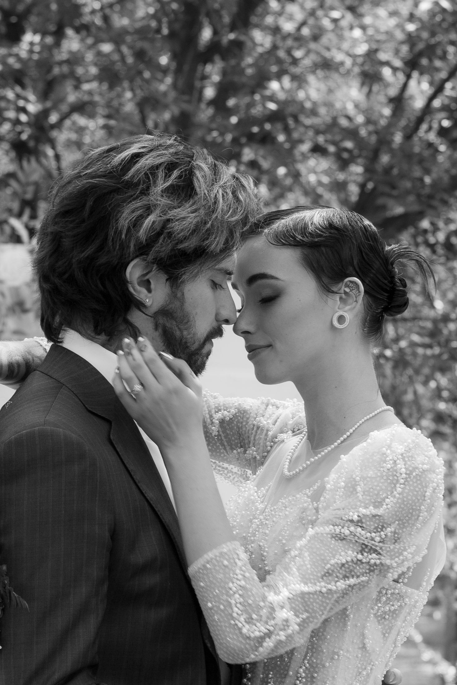 A romantic black and white wedding portrait showing an intimate moment between newlyweds.