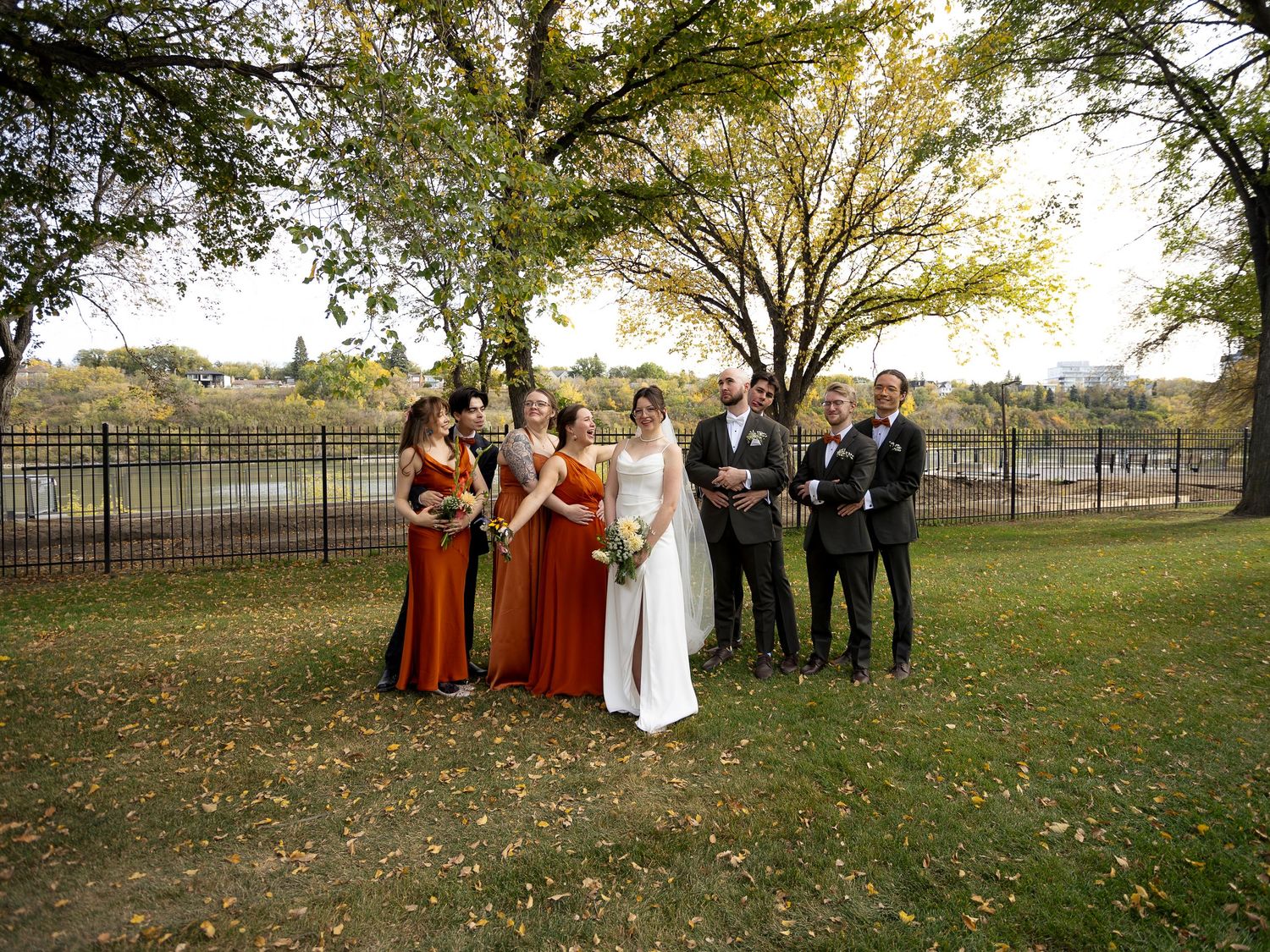 Wide shot of wedding party and guests gathered for outdoor autumn ceremony at the Besbourough Hotel in Saskatoon.