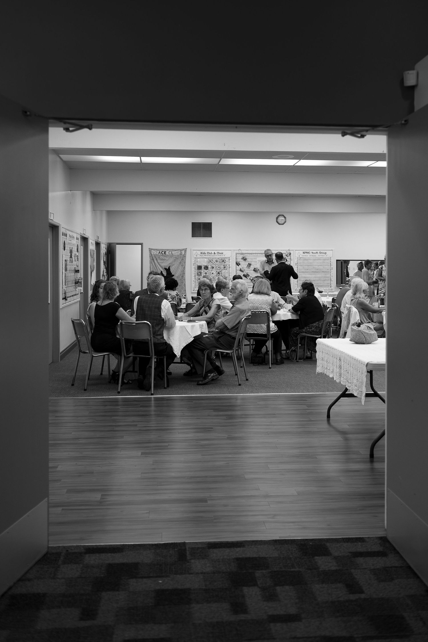 Black and white panoramic view of a reception hall with guests seated at tables.