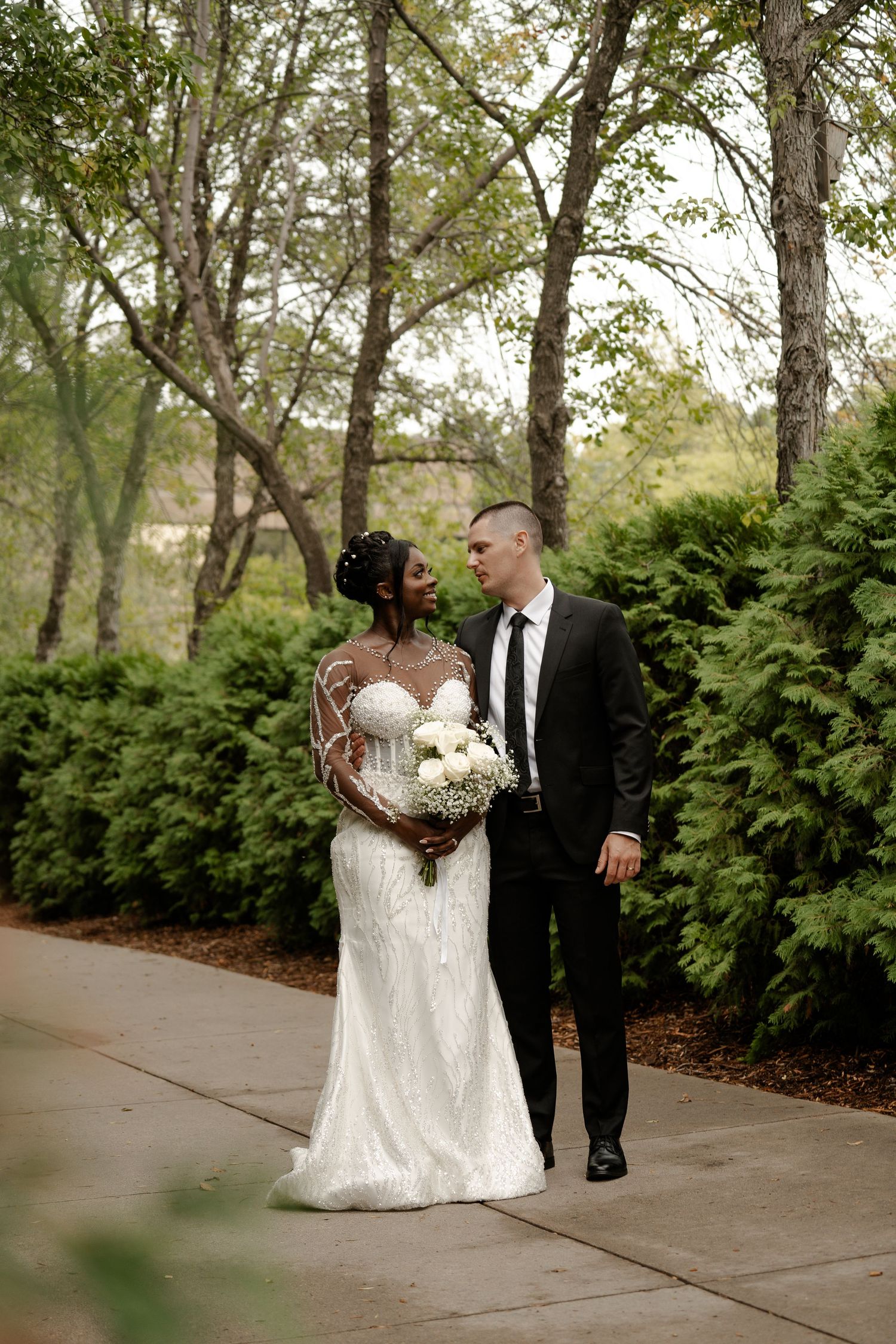 Garden pathway with lush greenery frames wedding couple's portrait session.