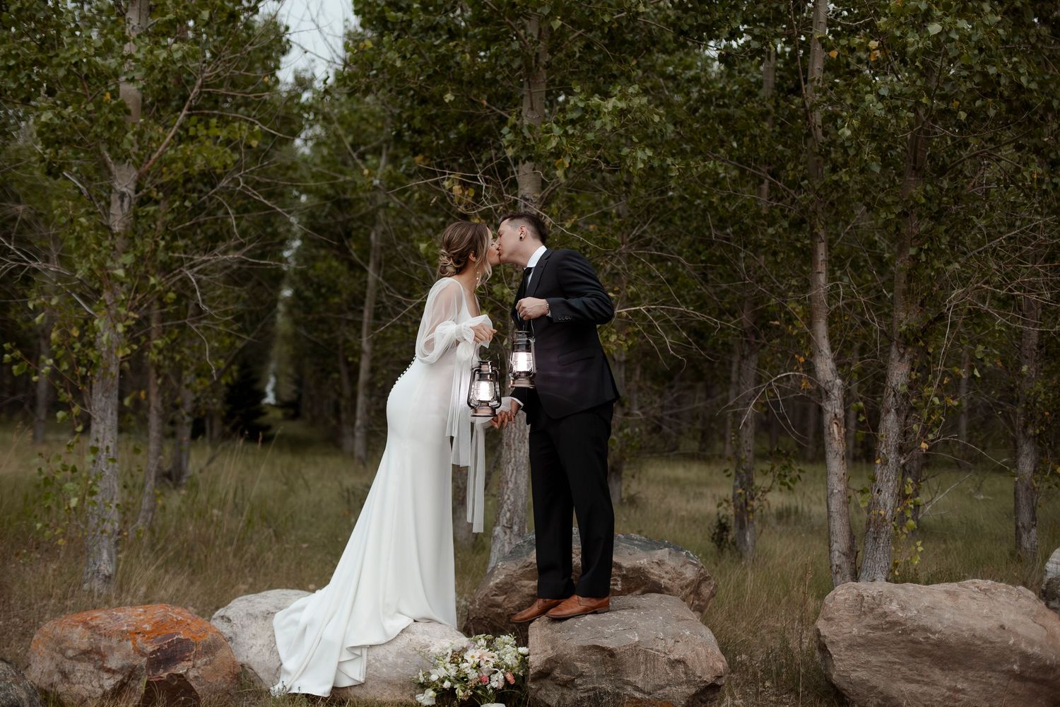 Wedding couple shares romantic moments in a wooded outdoor setting.