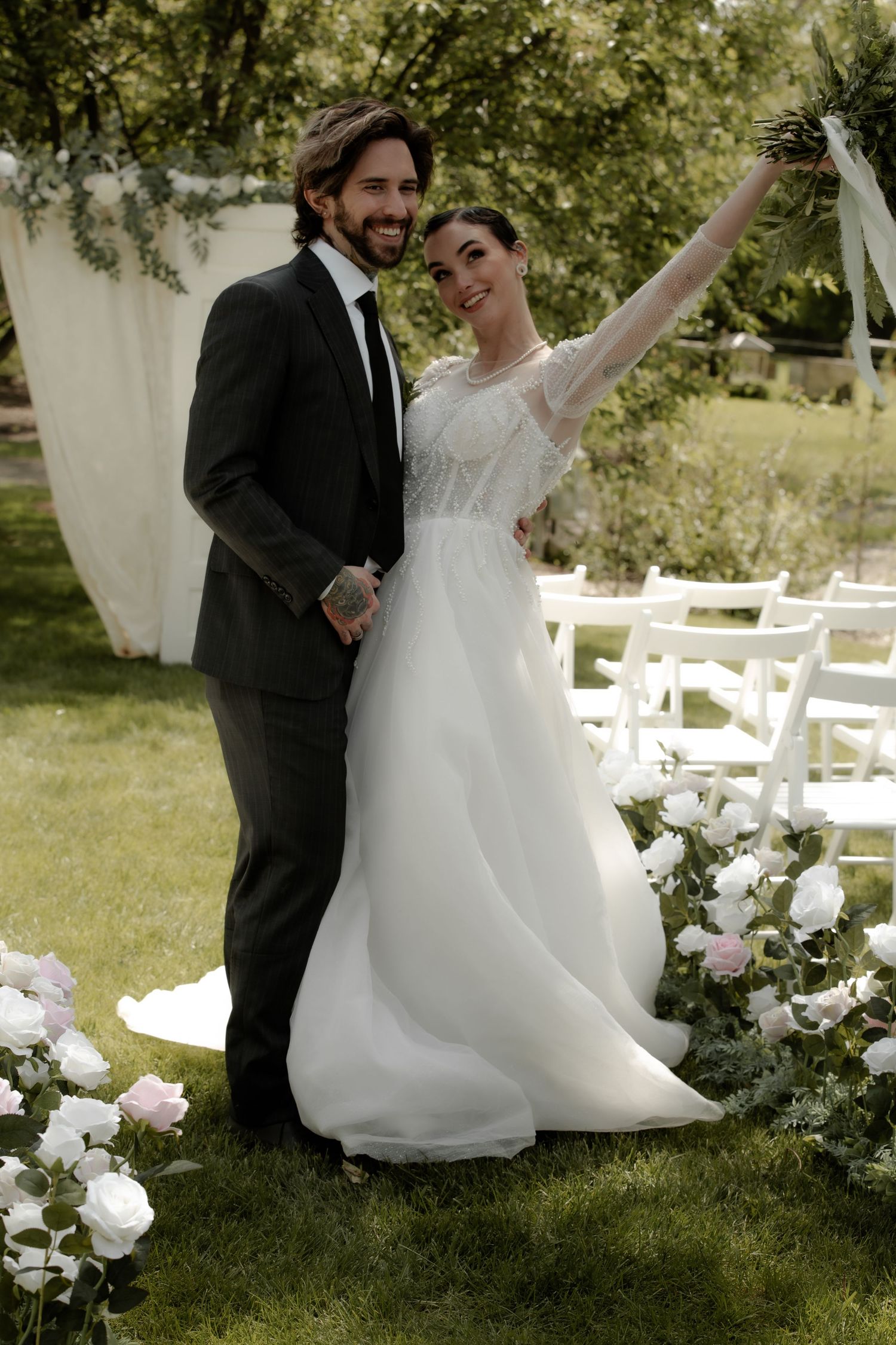 A wedding couple celebrates on a lawn with white chairs and floral decorations Cork & Crate Estates in Olds, Alberta.