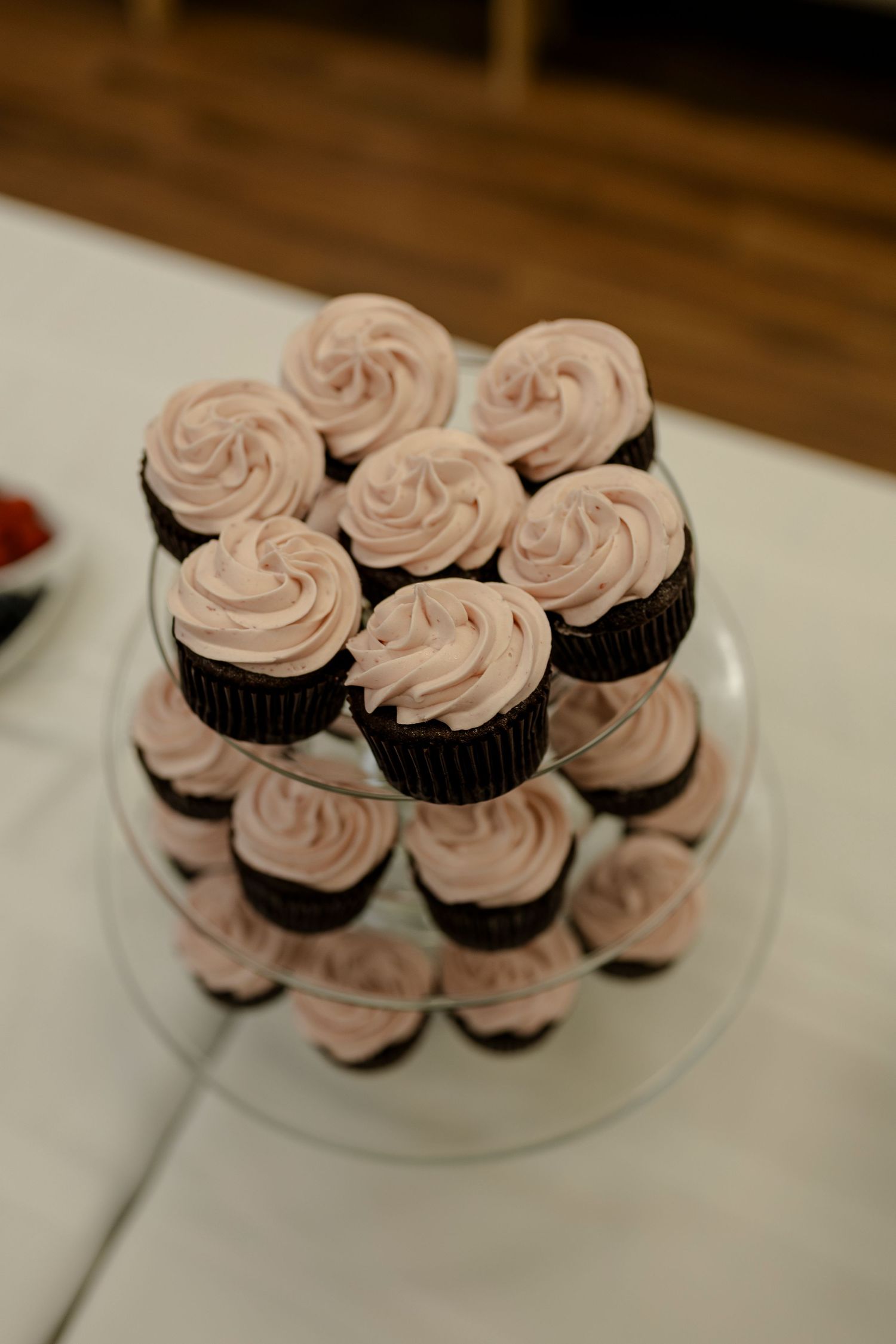 Elegant pink frosted cupcakes arranged on a white cake stand for a wedding reception.