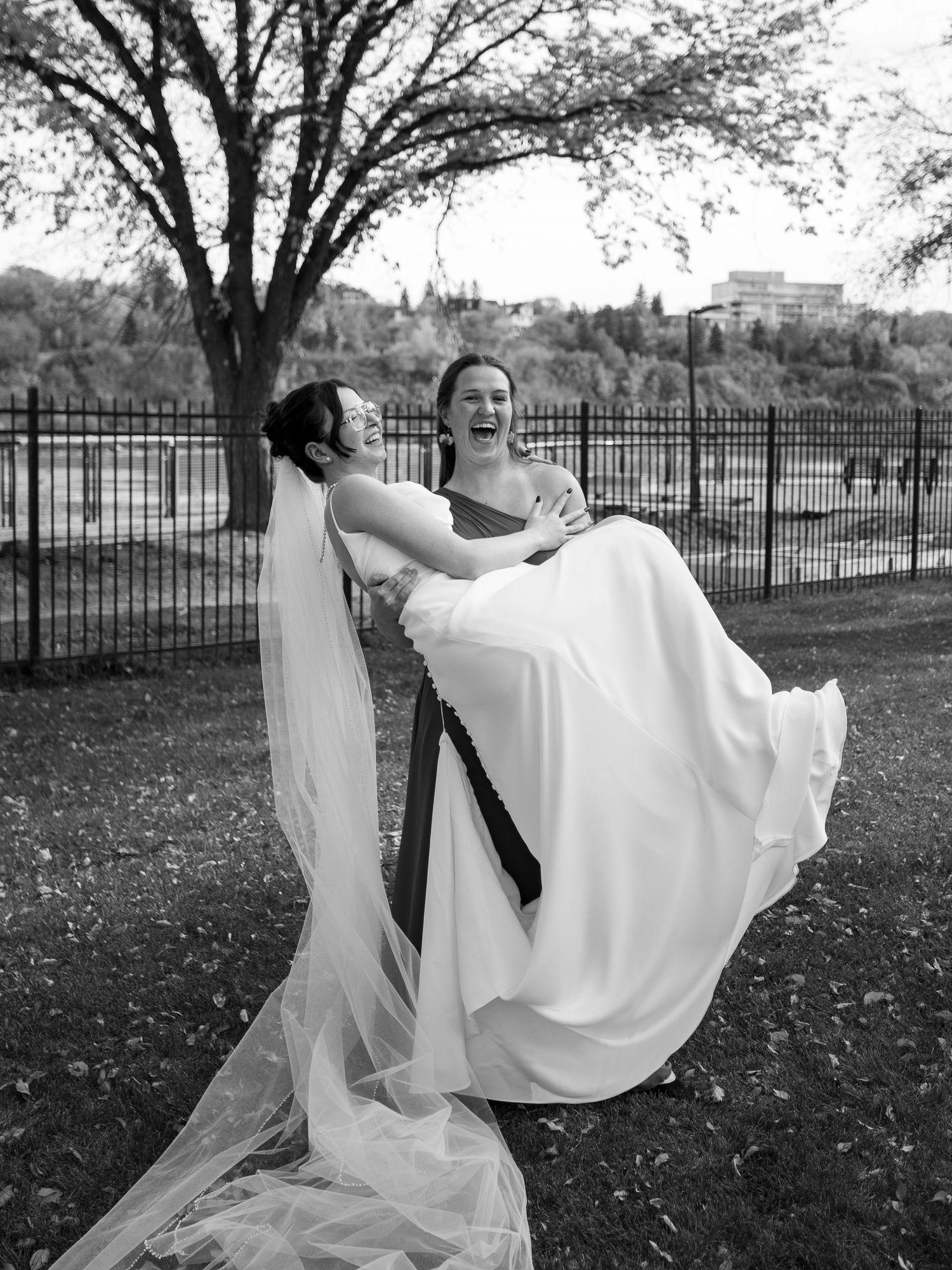 Couple performing a romantic dip pose during their wedding photoshoot in a park setting.