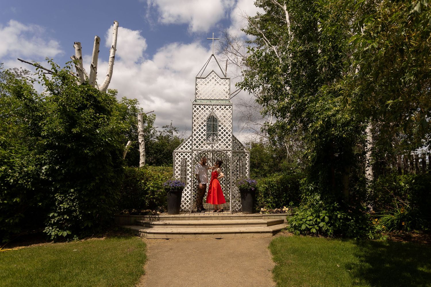 Garden pathway leading to a white gazebo structure under blue skies with puffy clouds at the Berry Barn in Saskatoon, Sask.