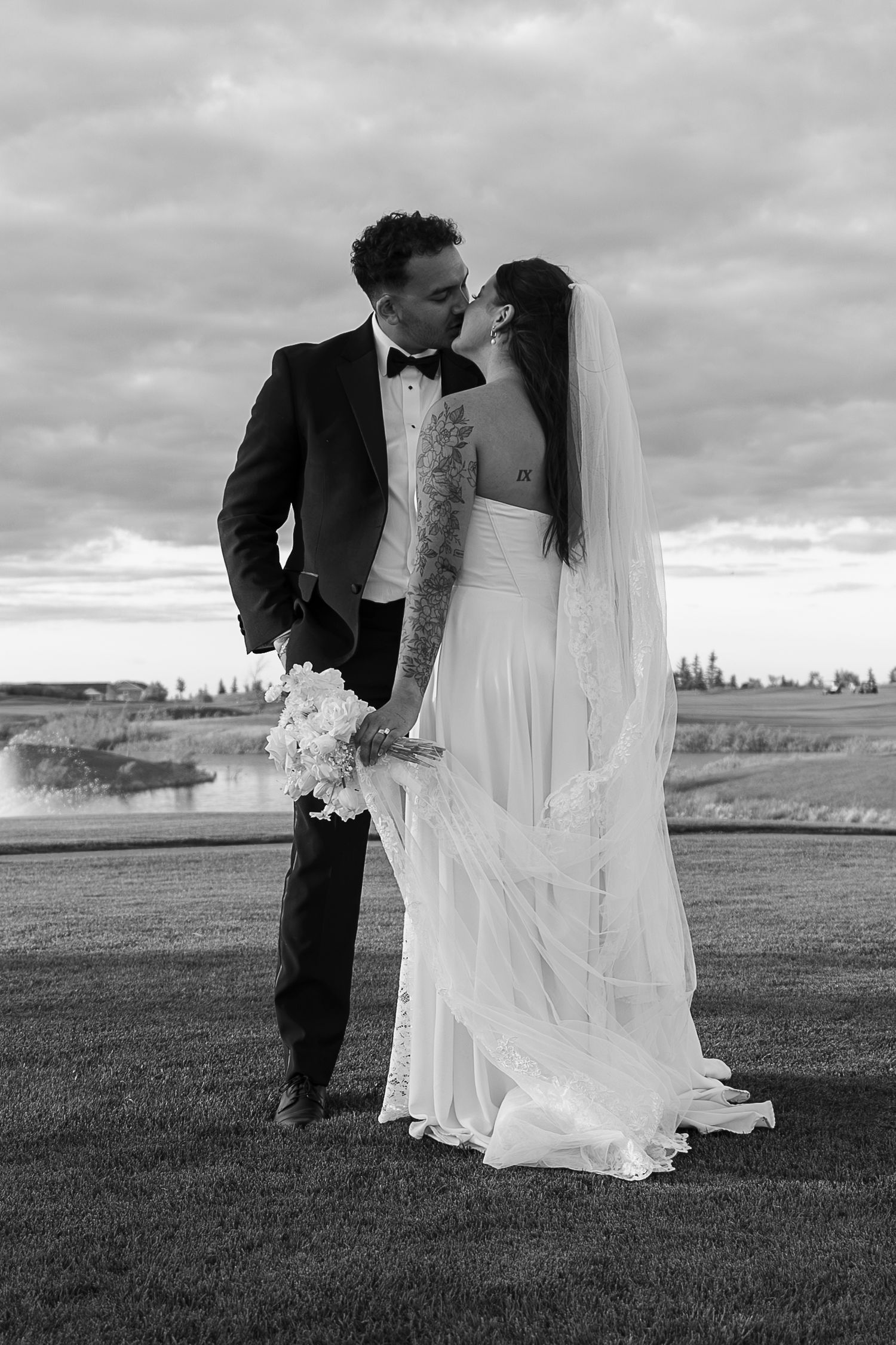 A black and white portrait of newlyweds embracing on a scenic golf course in Warmen, Saskatchewan.