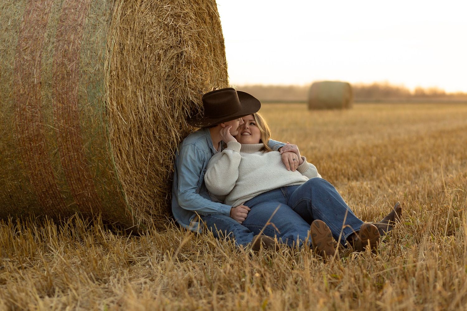 A cozy autumn moment shared while resting against a round hay bale in a harvested field in the Canadian Prairies.