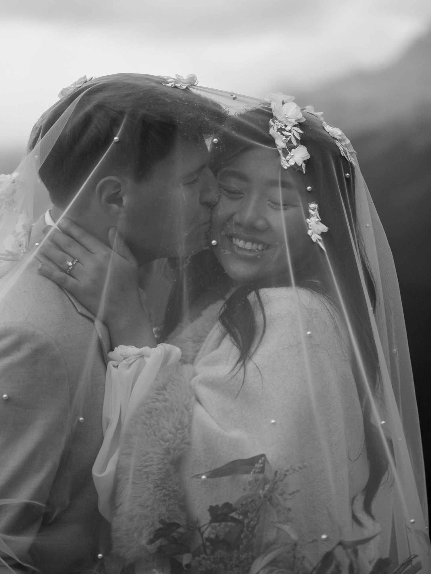 Romantic black and white portrait of couple sharing intimate moment under bridal veil at Peyto Lake in Banff National Park.