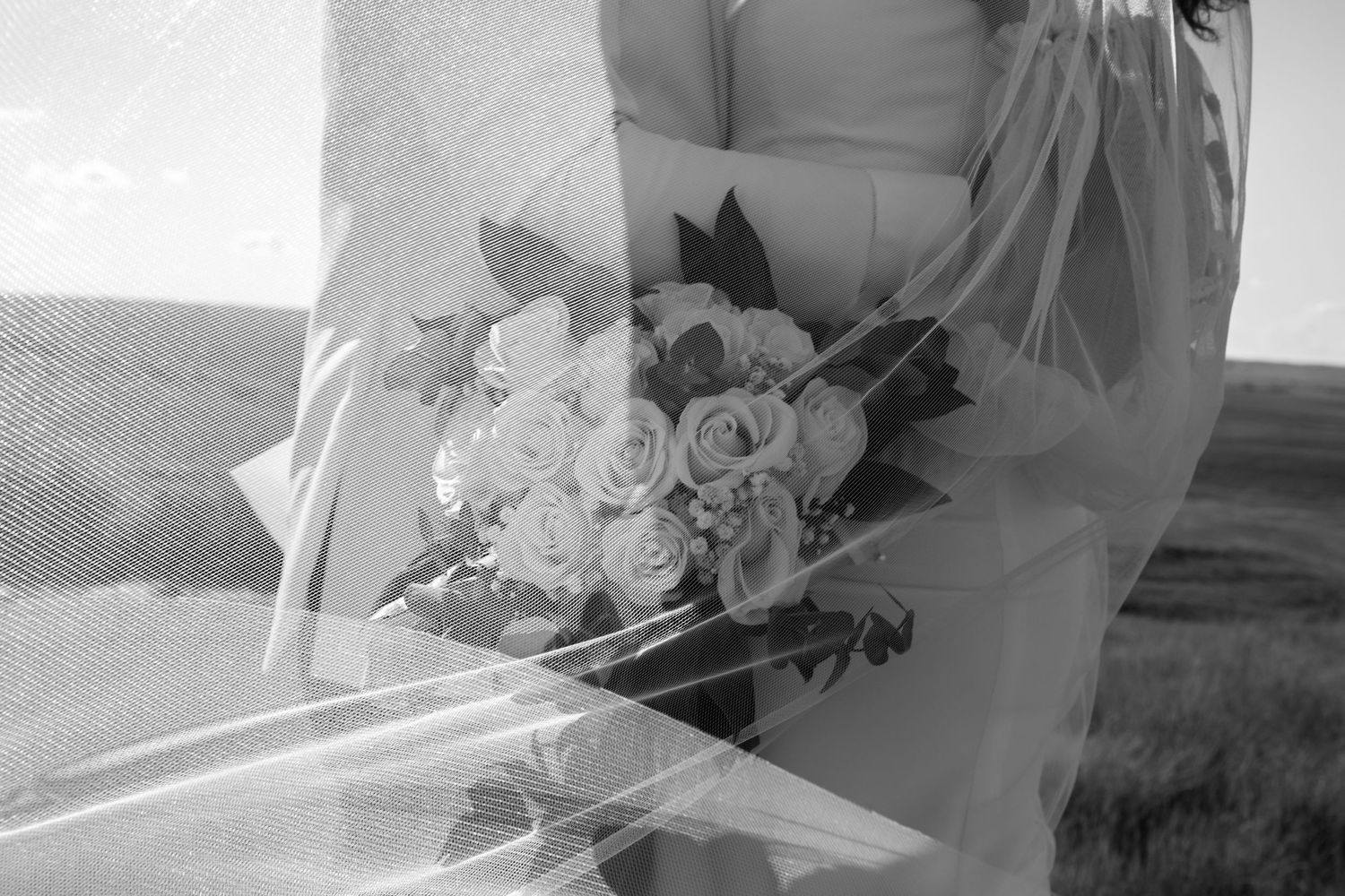 Black and white wedding photo of bouquets and floral arrangements in soft focus.
