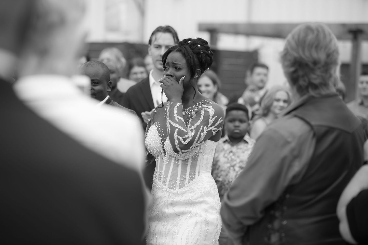 Black and white candid shot of wedding celebration with guests in background.