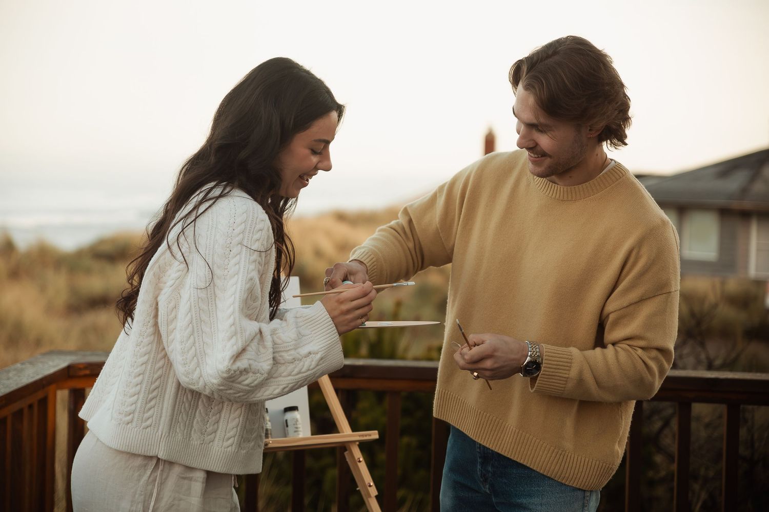 A couple enjoys a playful moment while looking at their phones outdoors.