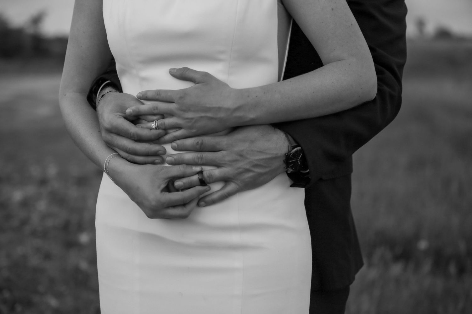 Intimate embrace captured in black and white showing formal wedding attire.