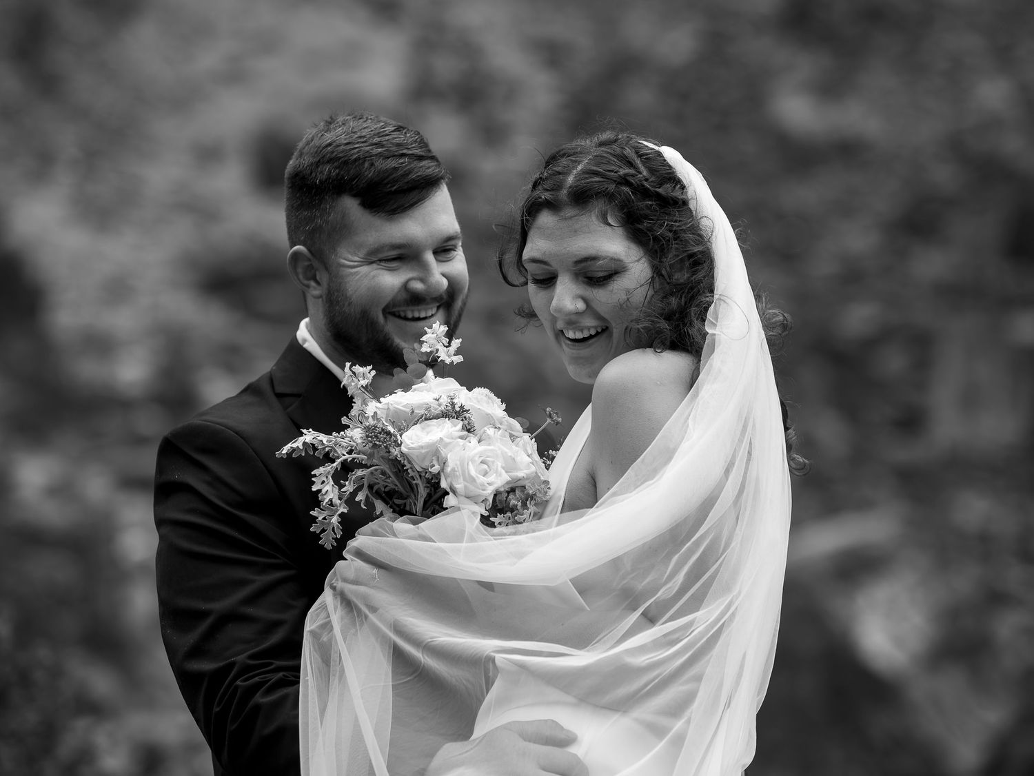 A black and white wedding photo capturing a romantic moment with flowing veil in Banff National Park.