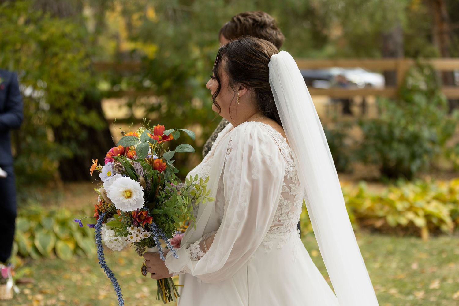 Bride in long-sleeved wedding dress walking through autumn garden setting at the Forestry Farm in Saskatoon, Saskatchewan.