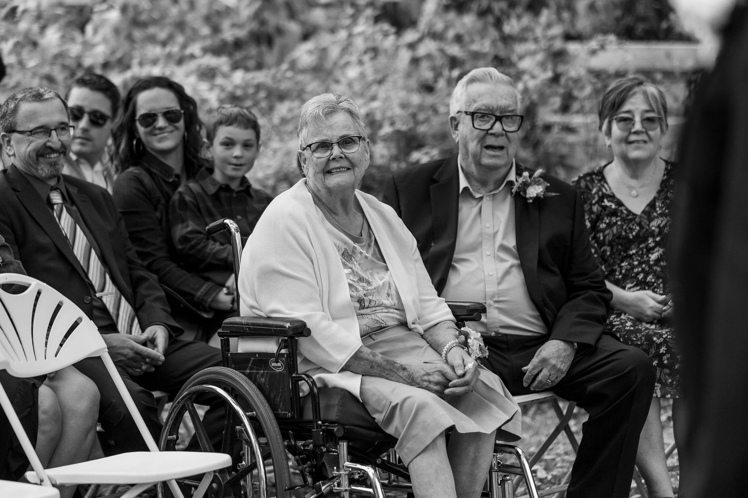 Wedding ceremony guests seated in rows watching the celebration in black and white at the Forestry Farm in Saskatoon, Saskatchewan.