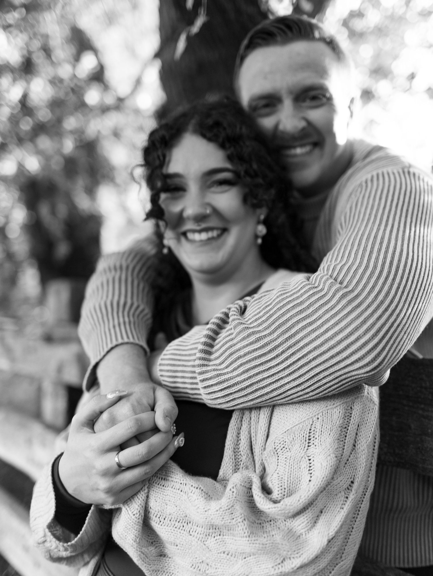 A joyful black and white portrait of a couple embracing and laughing together outdoors.