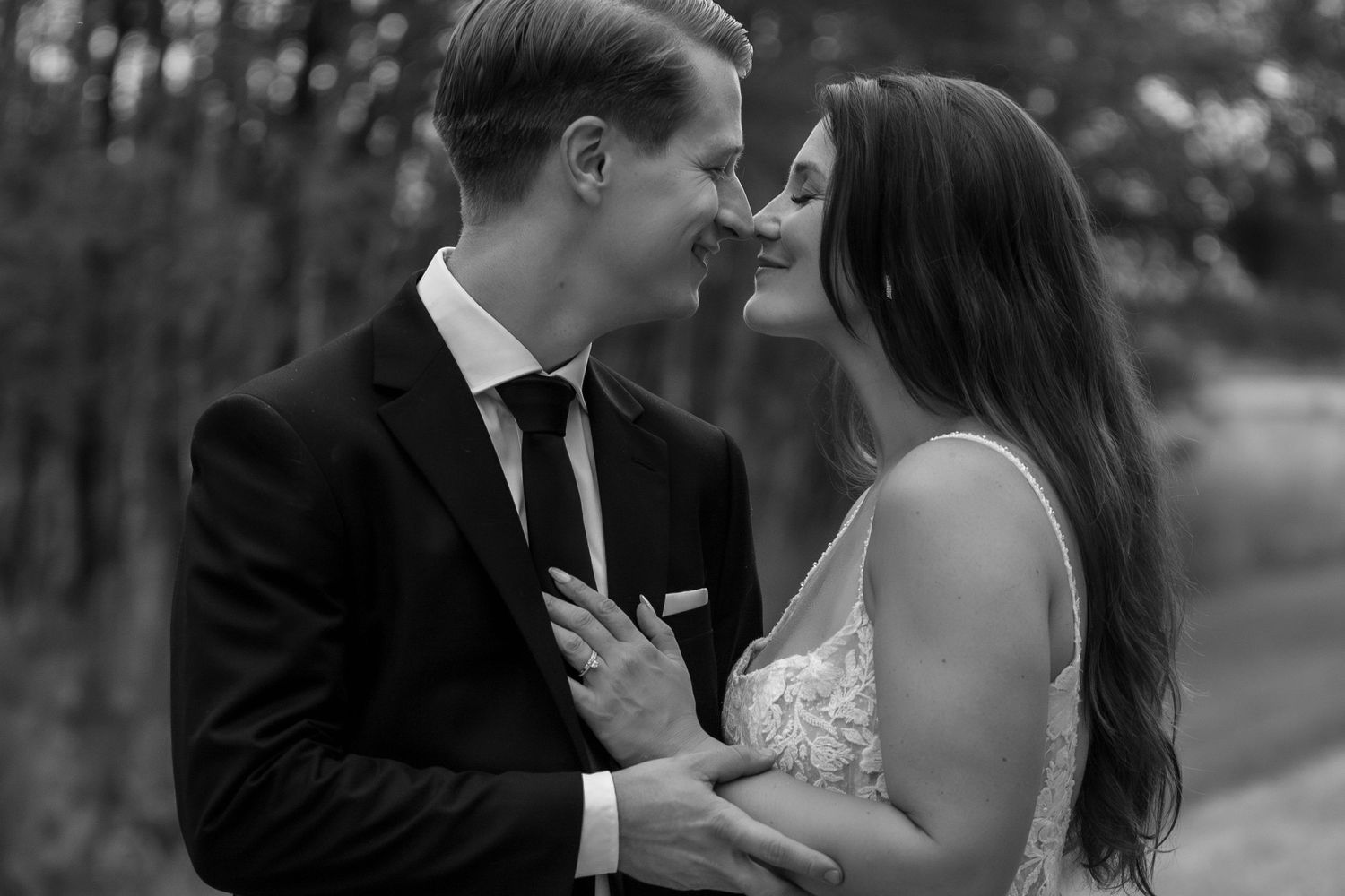 An elegant couple shares an intimate moment outdoors.