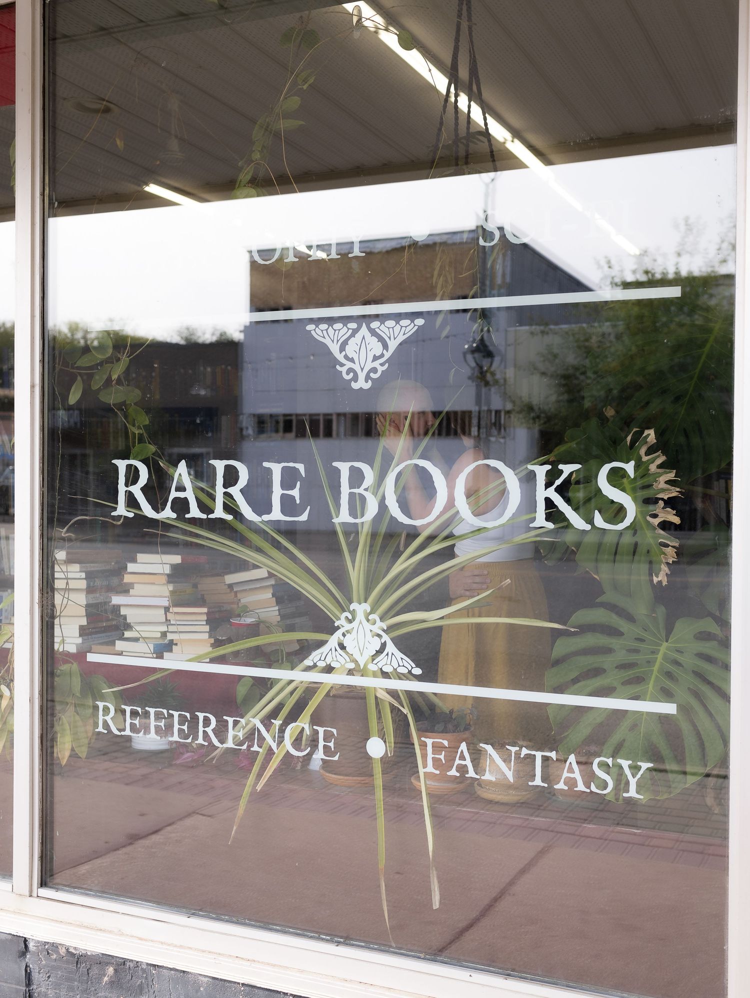 Storefront window display showing text 'RARE BOOKS' and 'REFERENCE FANTASY' in elegant lettering.