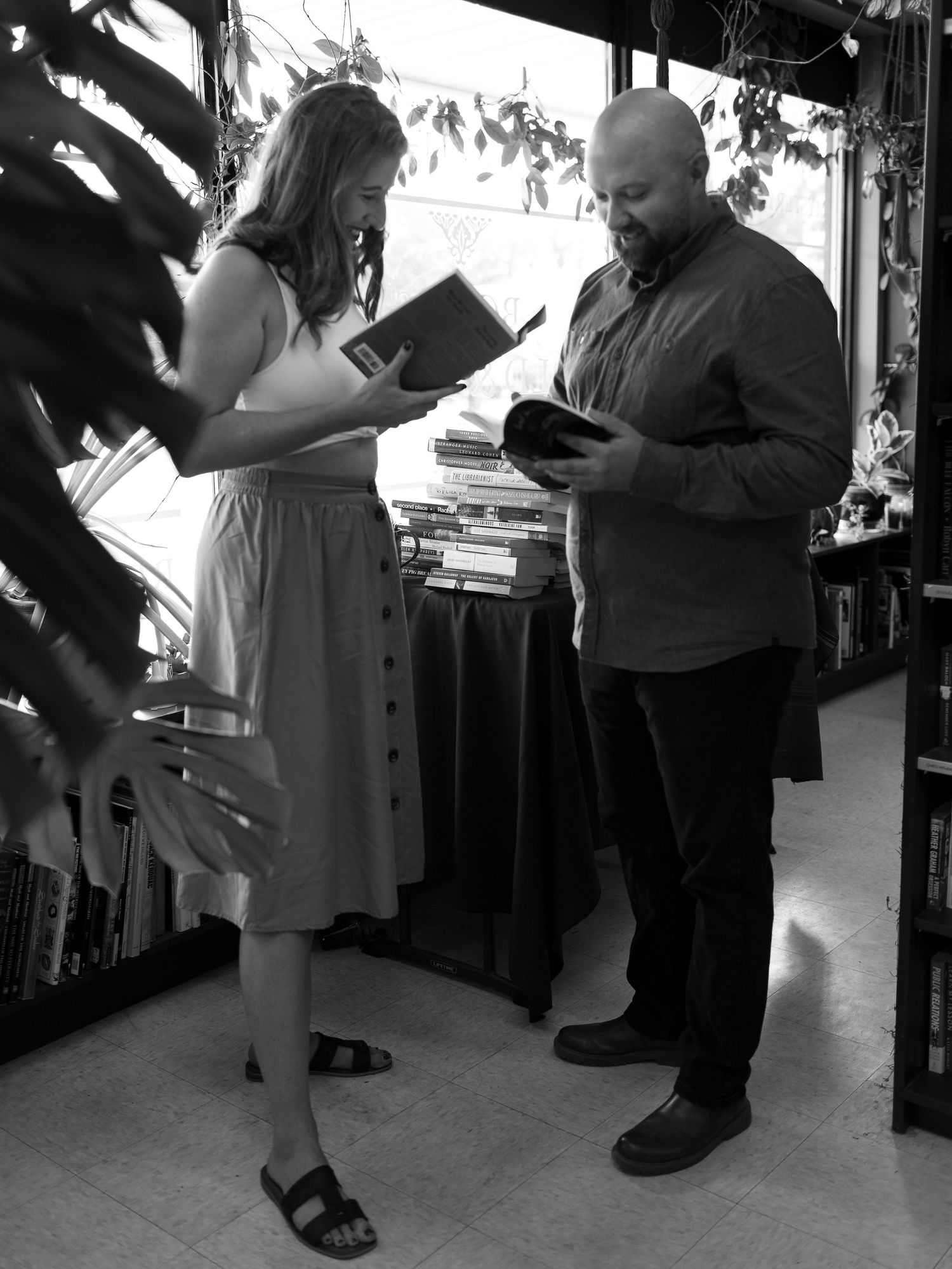Black and white photo of people browsing in a crowded bookstore aisle.
