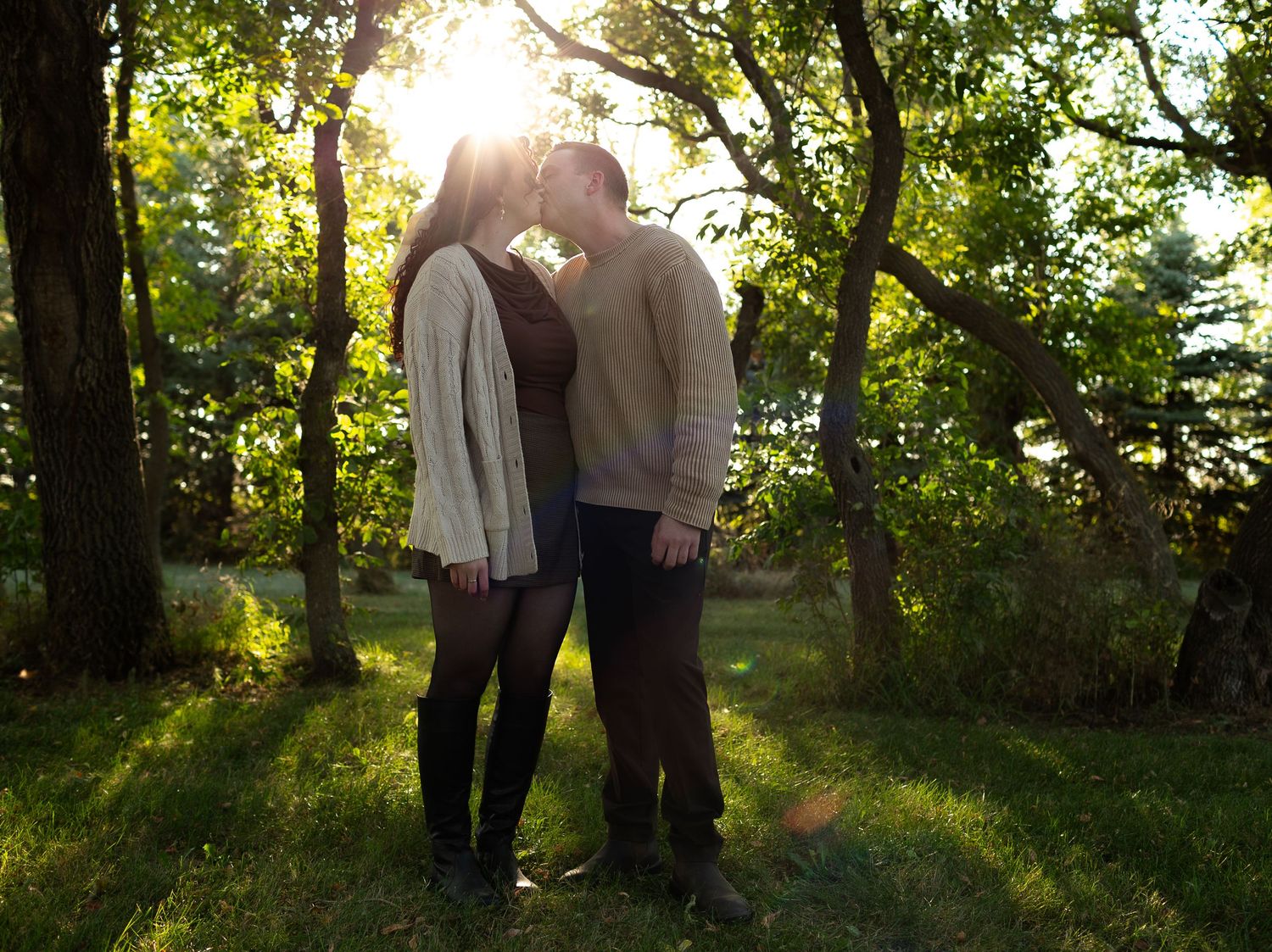 A romantic couple shares tender moments in sunlit woodland during golden hour.
