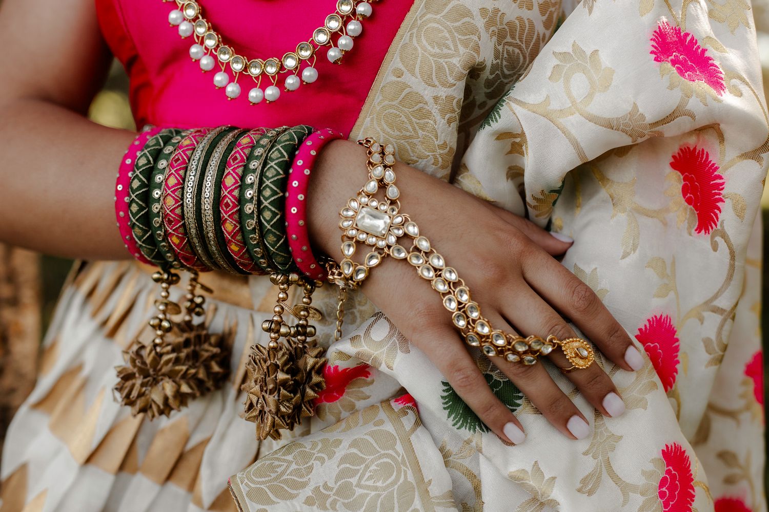 Ornate bridal jewelry and bangles adorned with pearls and traditional designs in pink and gold.