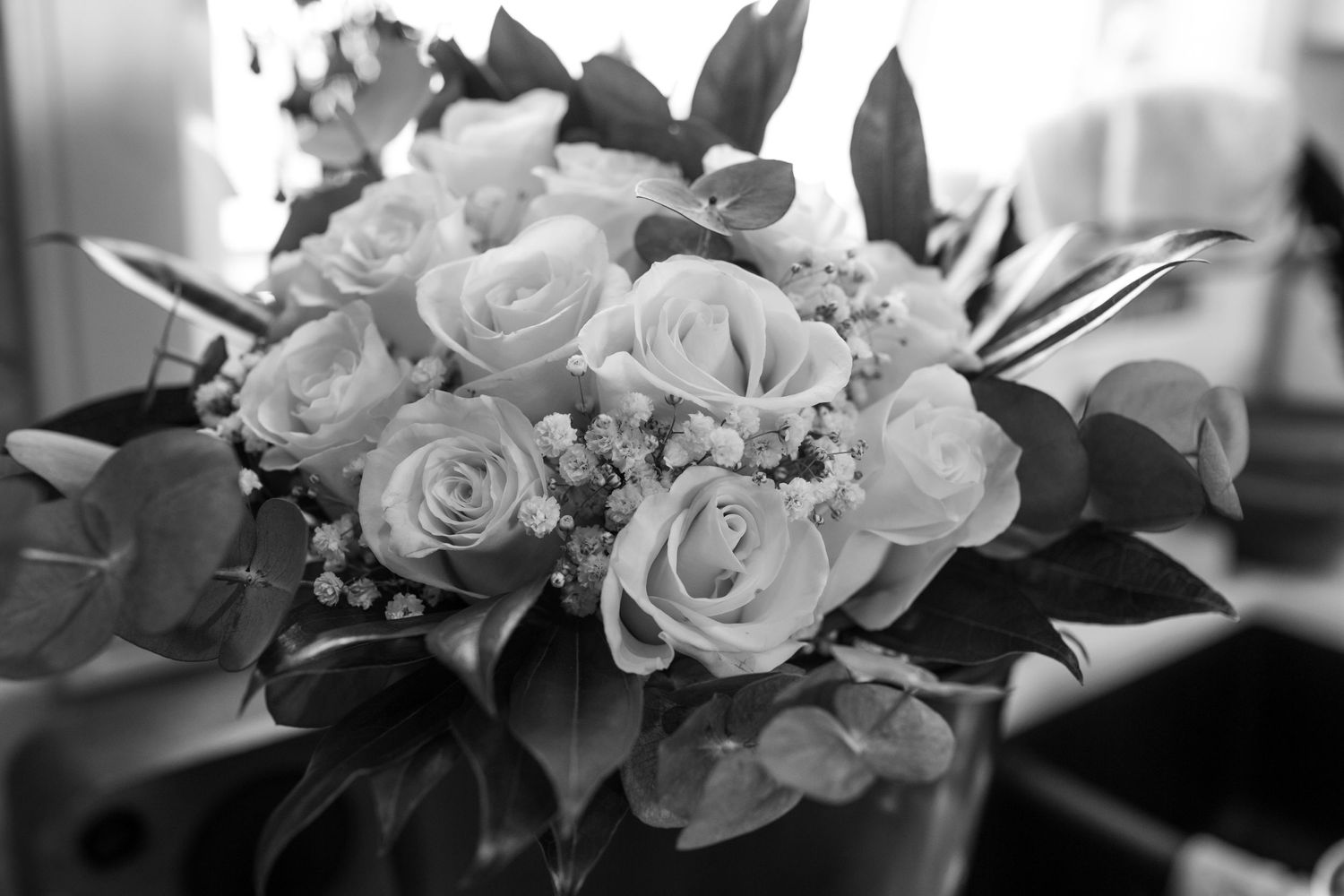 Close-up of white roses and floral arrangements in black and white.