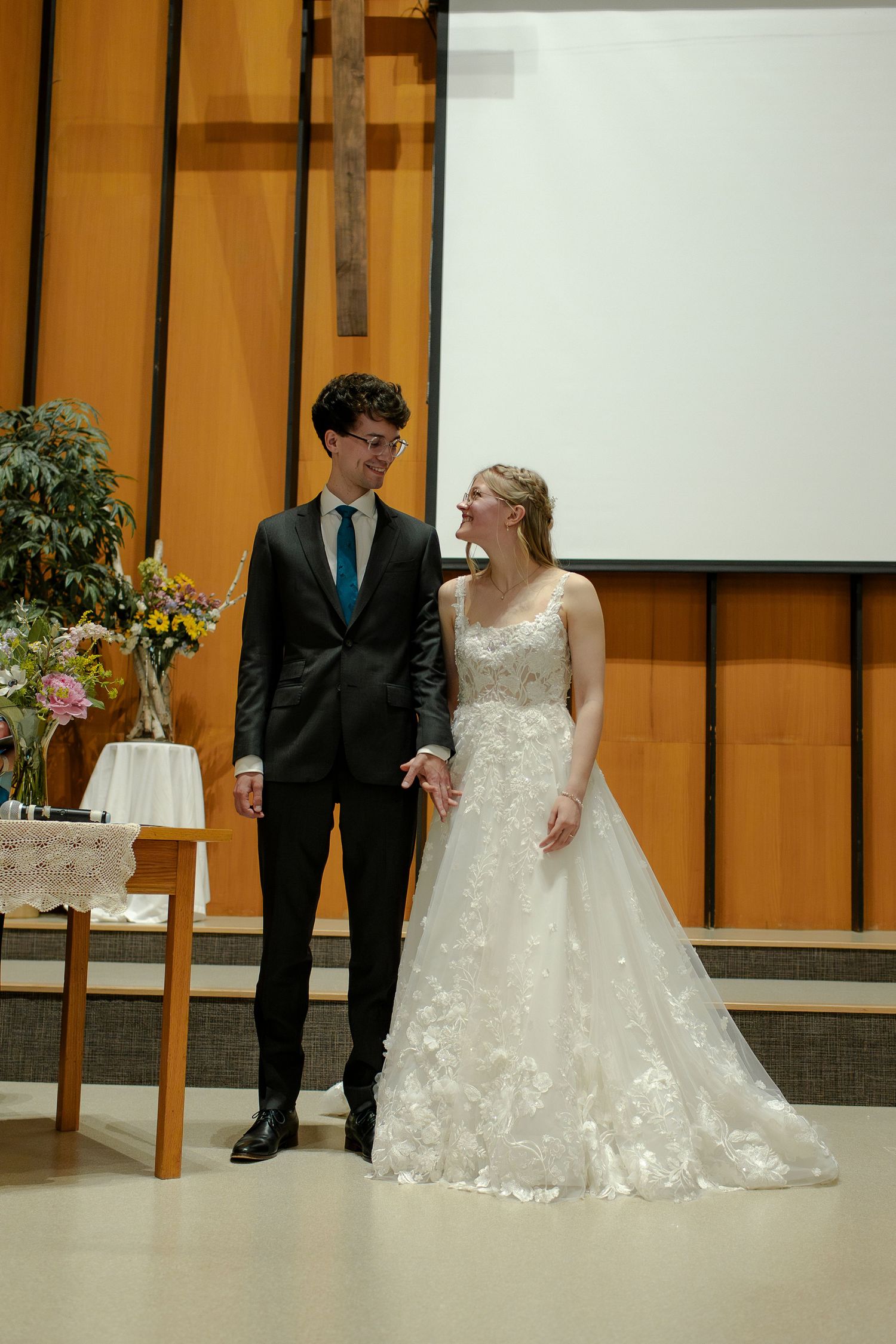 A wedding ceremony in a modern church space with wood paneled walls and minimalist decor.