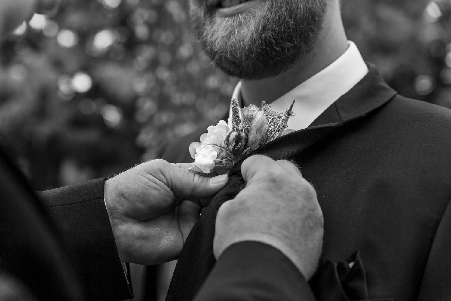 Close-up shot of a boutonniere being pinned on a black suit jacket at the Forestry Farm in Saskatoon, Saskatchewan.