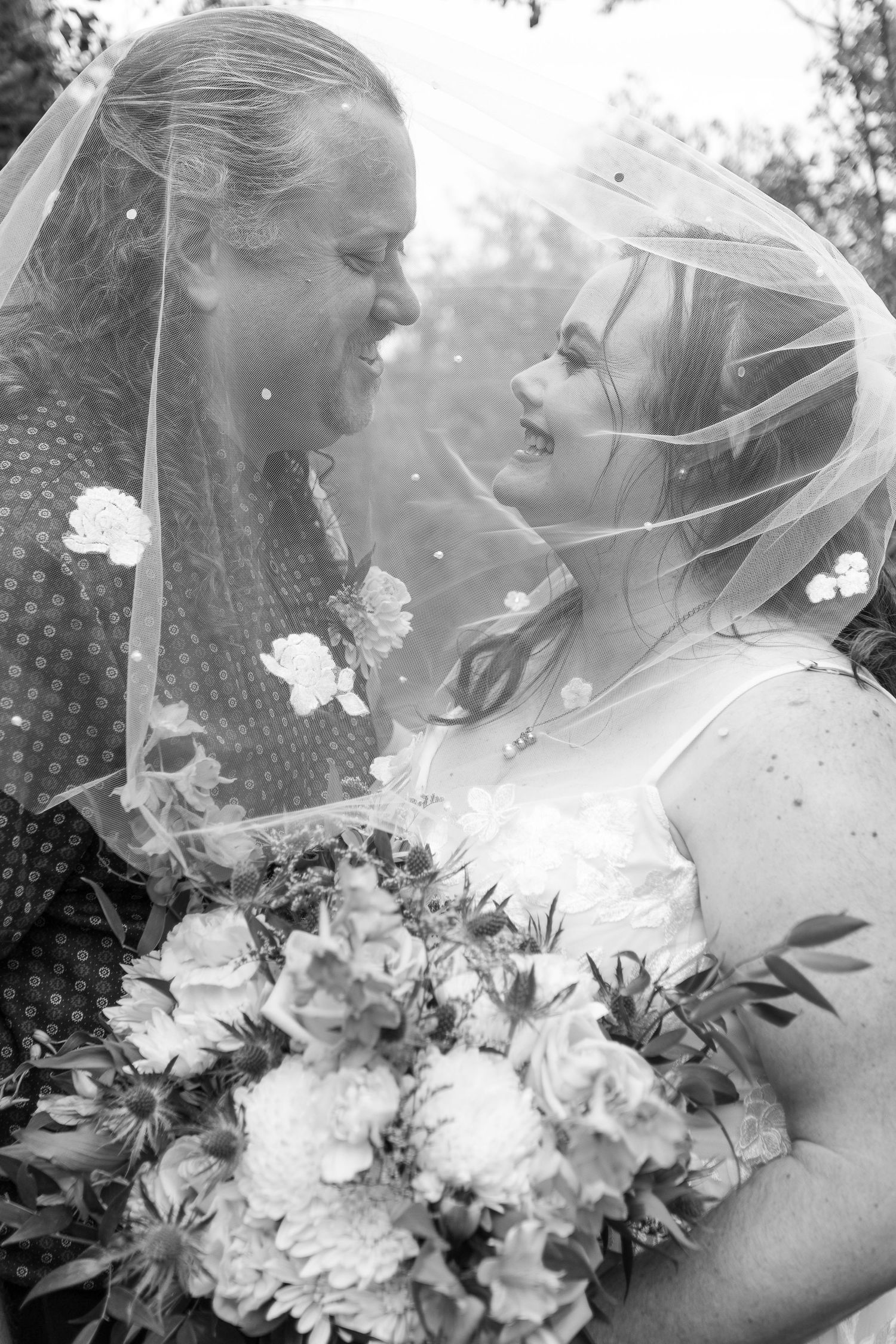 A close-up shot of a wedding bouquet with white flowers under a delicate veil.