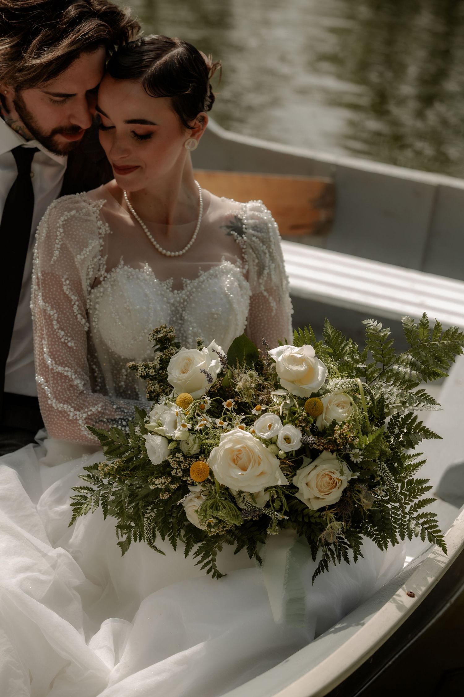 Wedding couple holding an elegant white rose and greenery bouquet in natural outdoor lighting Cork & Crate Estates in Olds, Alberta.