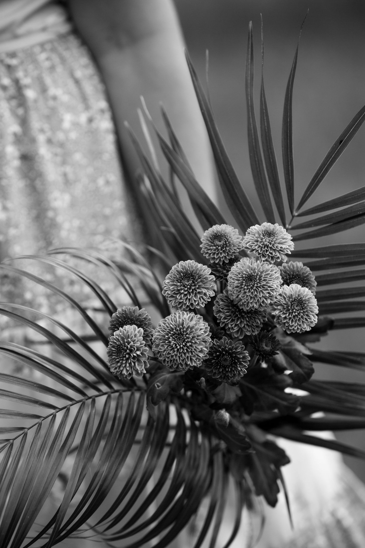 Black and white floral arrangement featuring chrysanthemums and palm fronds.