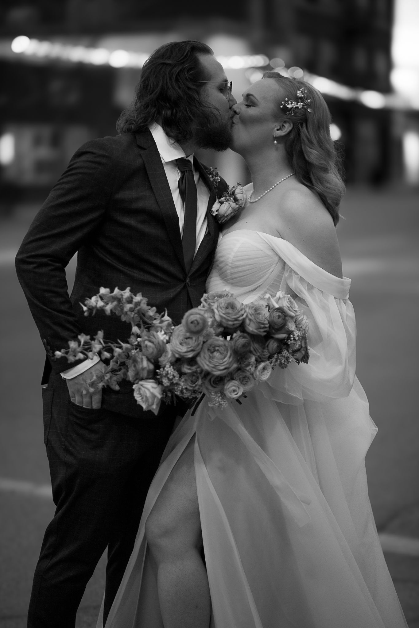 Black and white wedding photography captures intimate moments with floral bouquet.