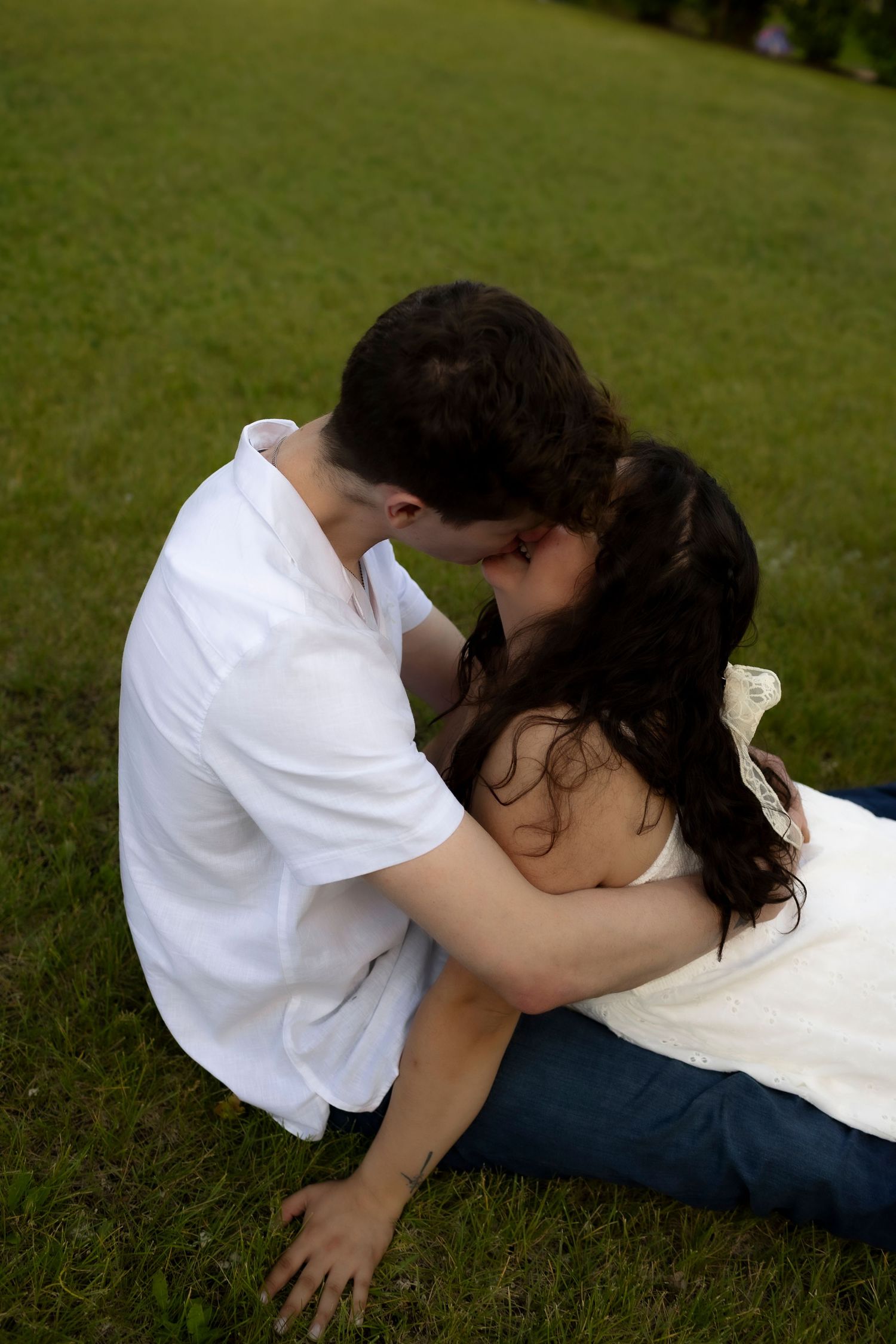 A couple embraces on grassy lawn during an intimate outdoor photoshoot.