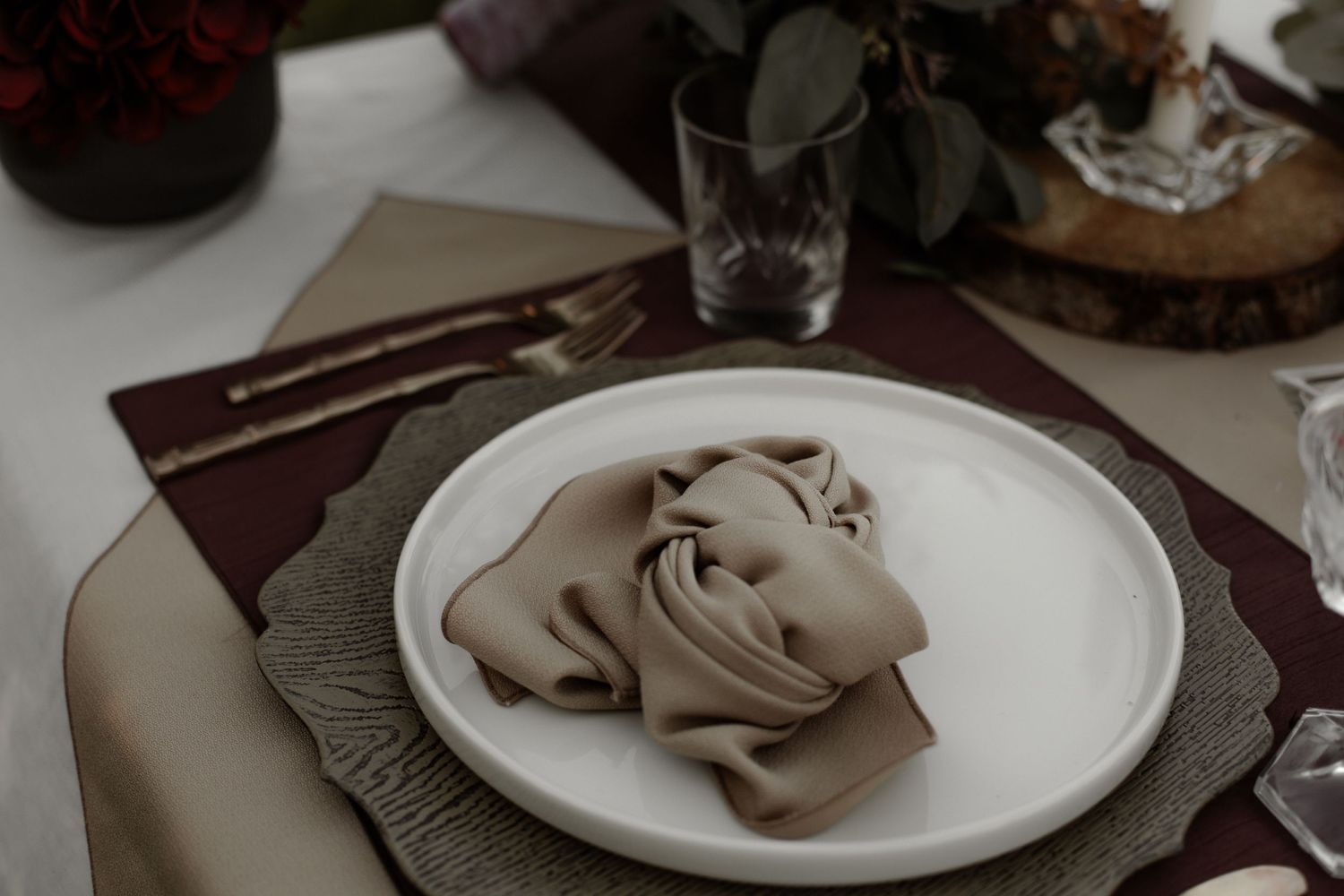 Elegant table setting with folded napkins and white plates on a dark surface.