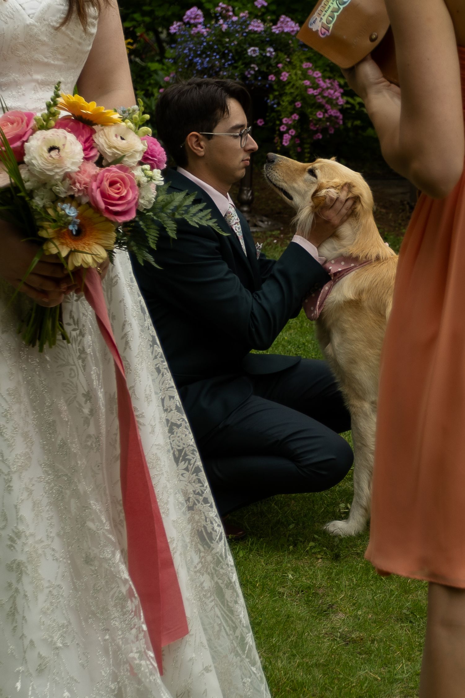 Wedding party with colorful bouquets and a golden retriever dog on grass.