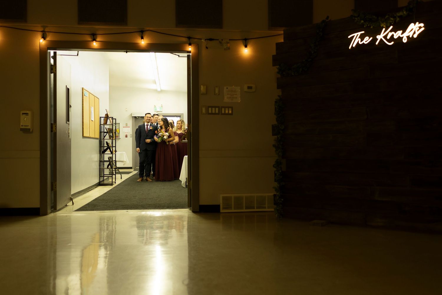 The Kraft venue entrance glowing at night with warm string lights and neon sign welcoming guests inside.
