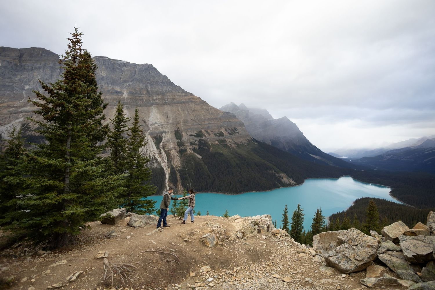 Hikers photographing stunning turquoise Peyto Lake from Bow Summit viewpoint in Banff National Park, Alberta.