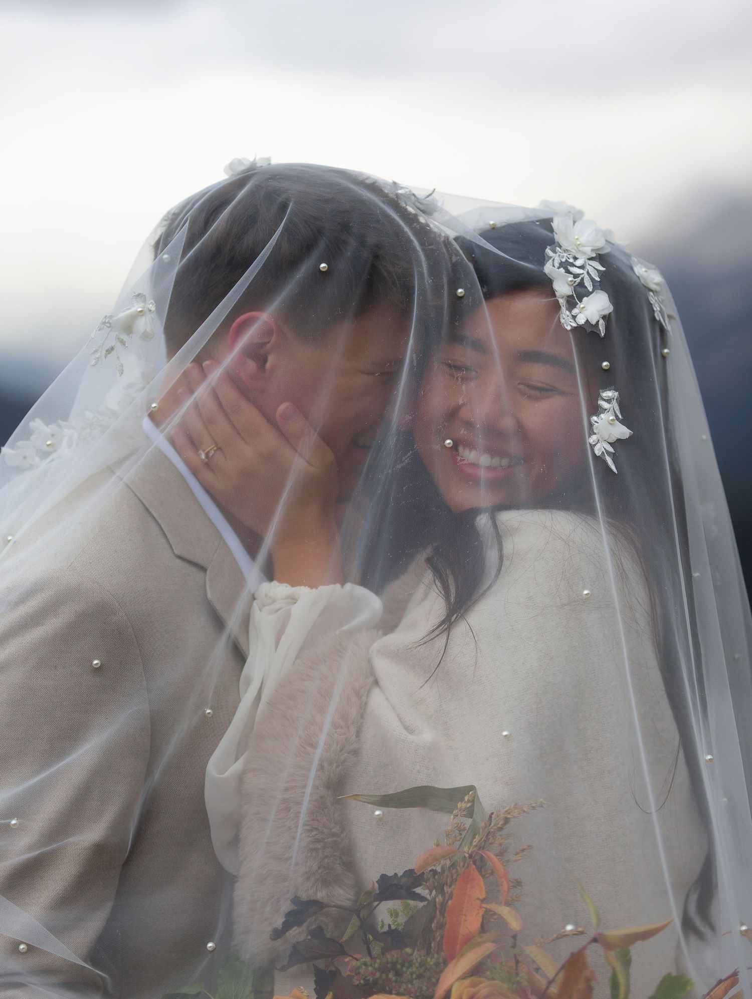 Romantic moment under a delicate wedding veil with soft lighting and floral details at Banff National Park on the Canadian Rockies.