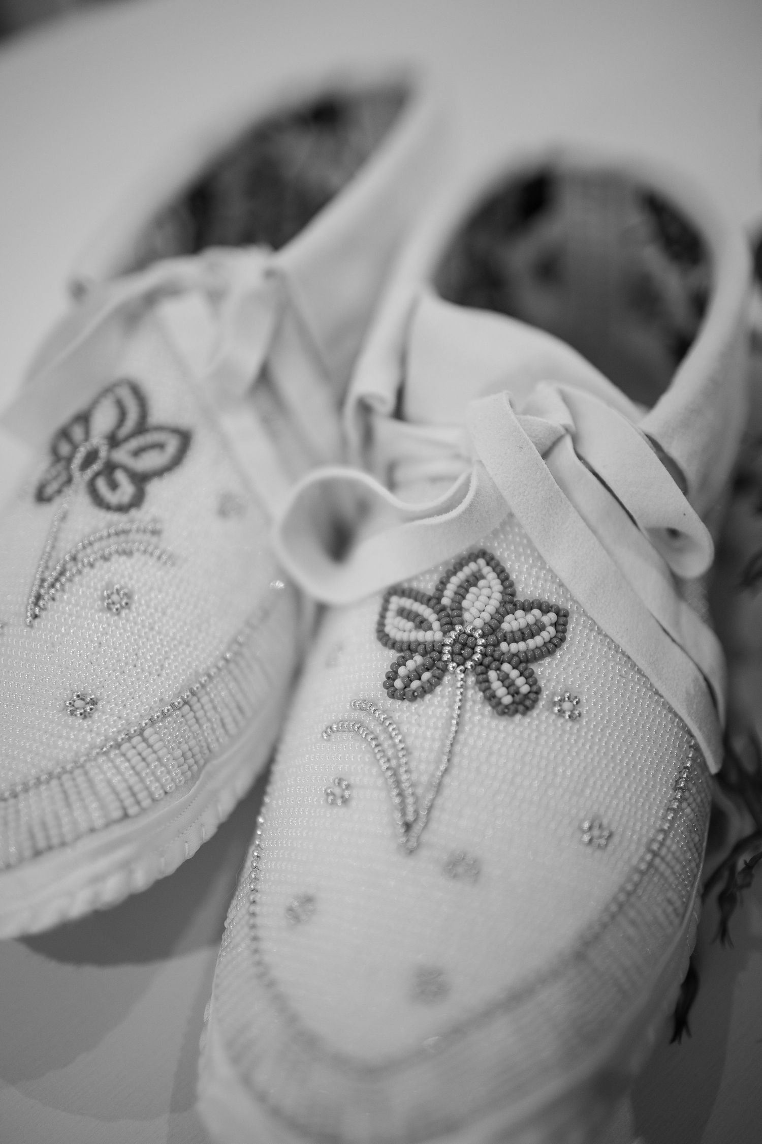 Close-up detail of delicate beaded floral designs on white wedding shoes.