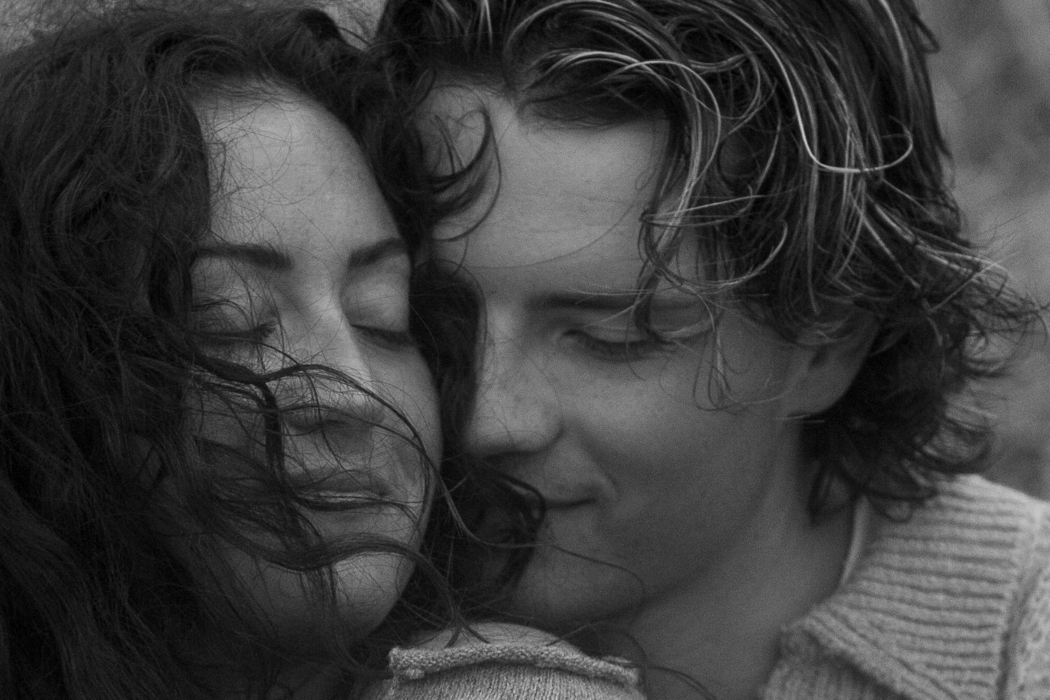 Intimate black and white portrait of a romantic couple sharing a tender moment with their faces close together.
