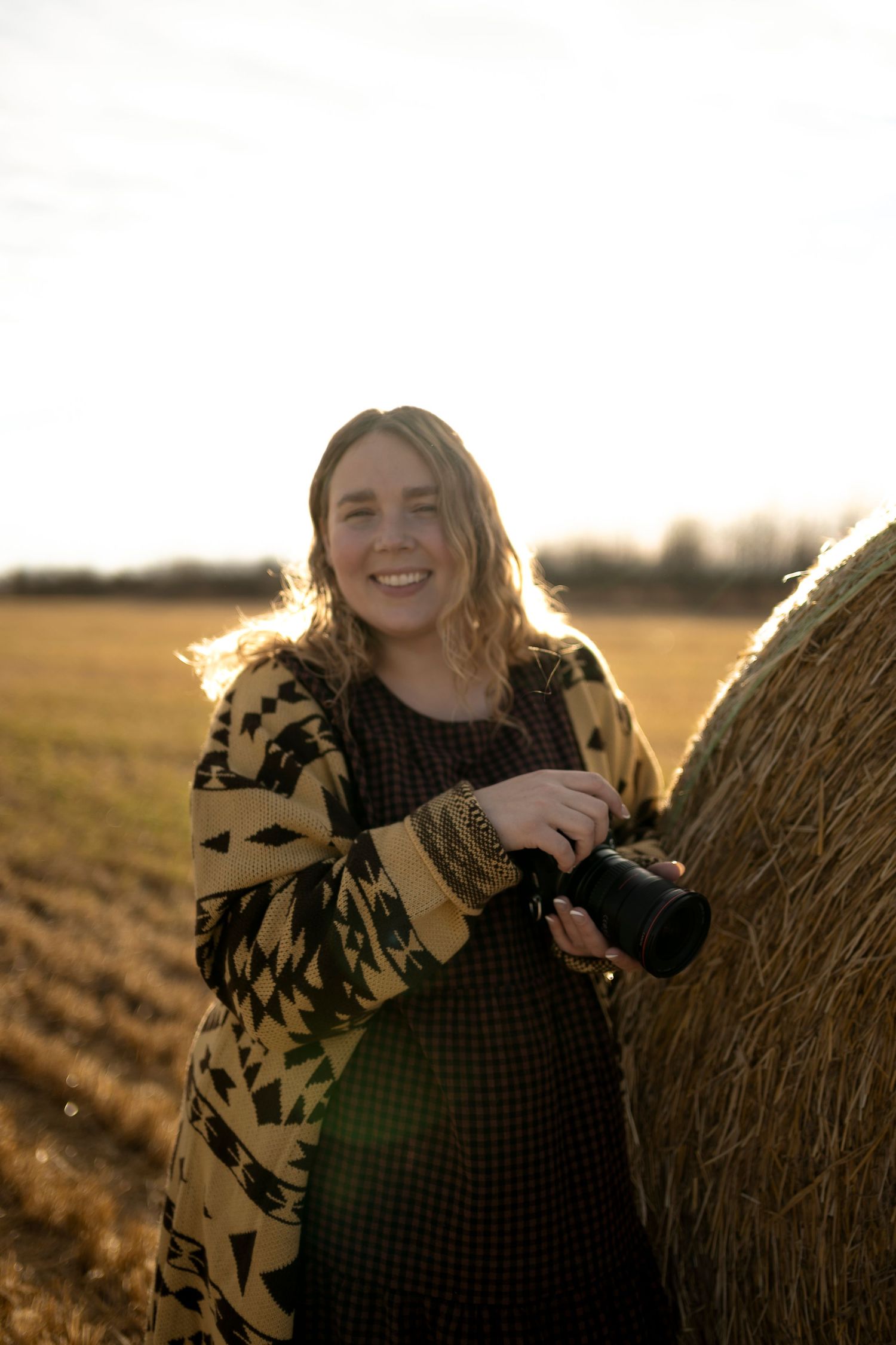 Outdoor photography session against hay bales during sunset with warm lighting.