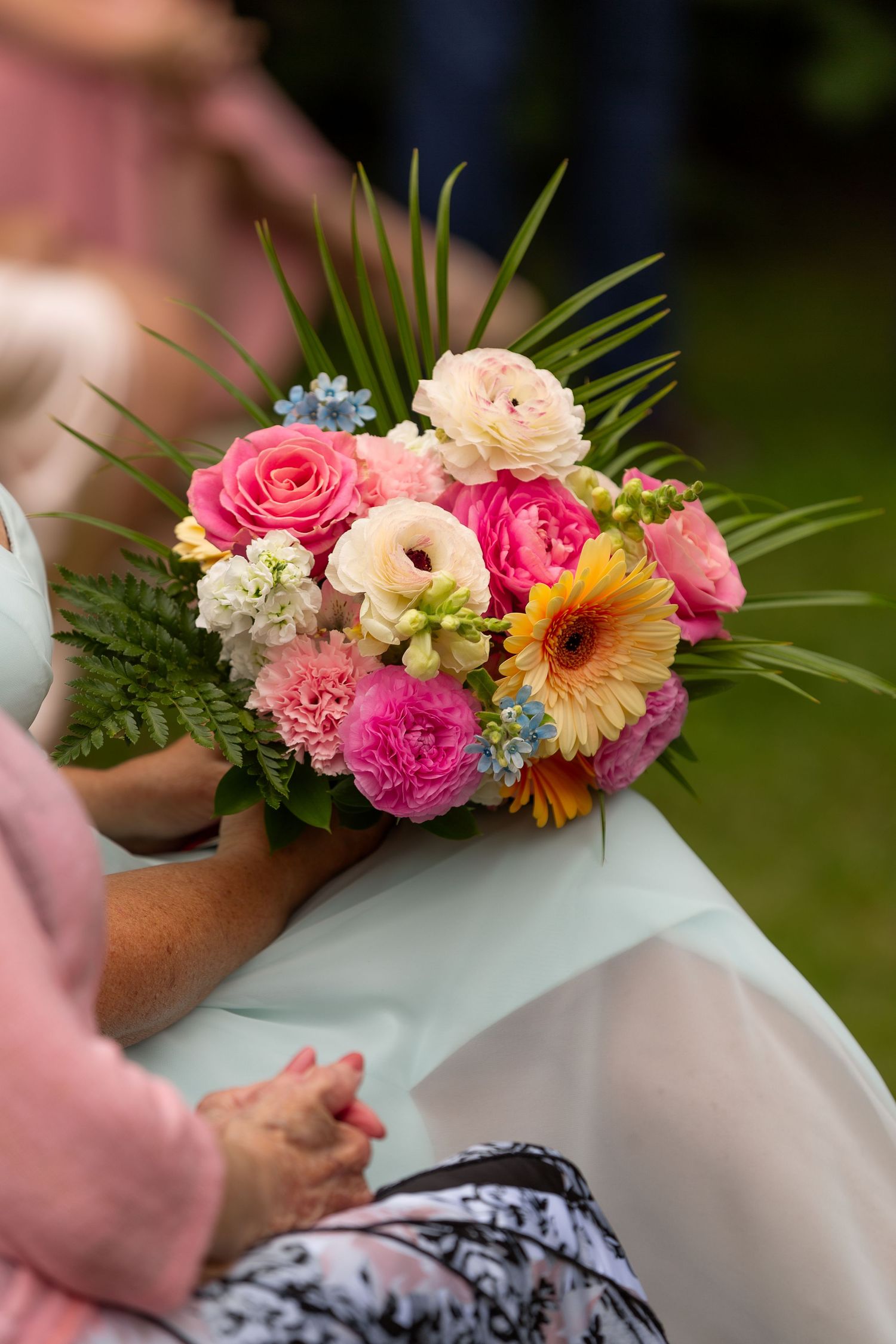Vibrant wedding bouquet with pink roses, gerbera daisies and tropical greenery.
