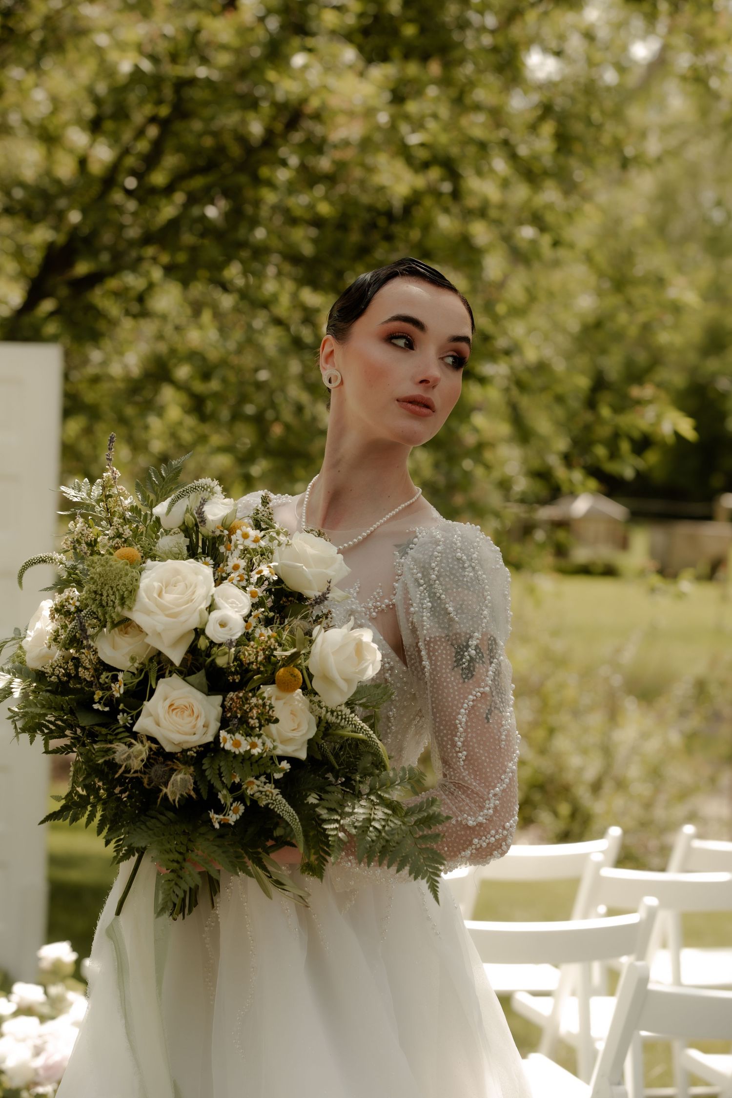 Bridal portrait with lush white rose bouquet against sunlit outdoor garden backdrop Cork & Crate Estates in Olds, Alberta.