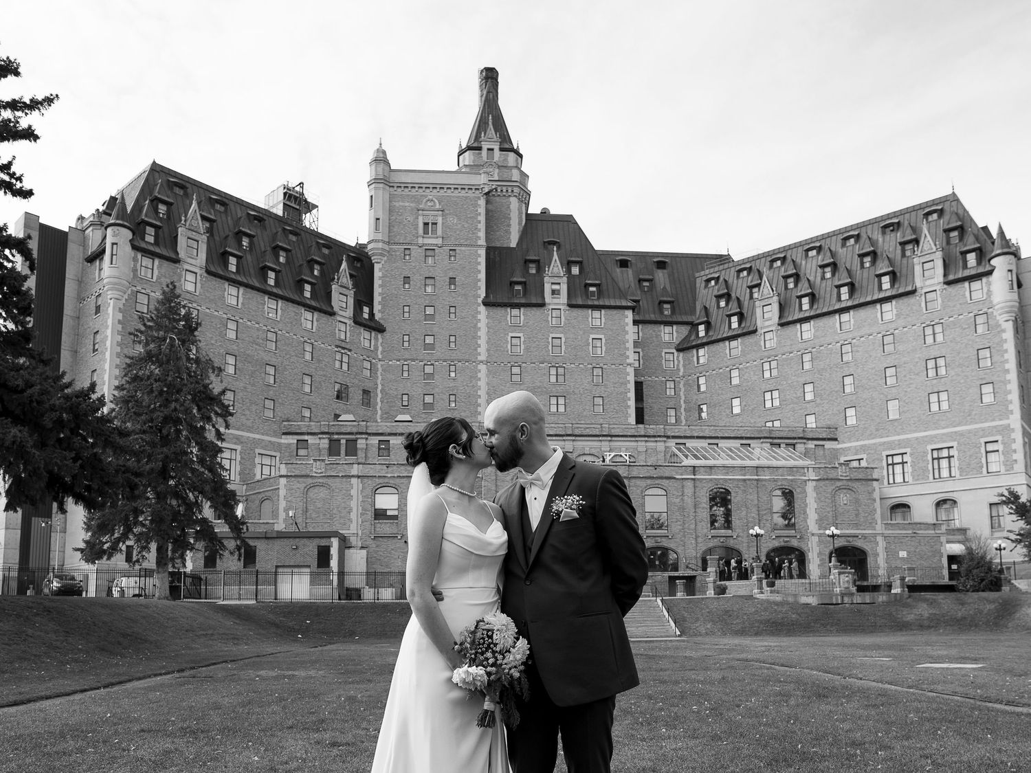 Historic stone building with tower provides majestic backdrop for wedding photos.