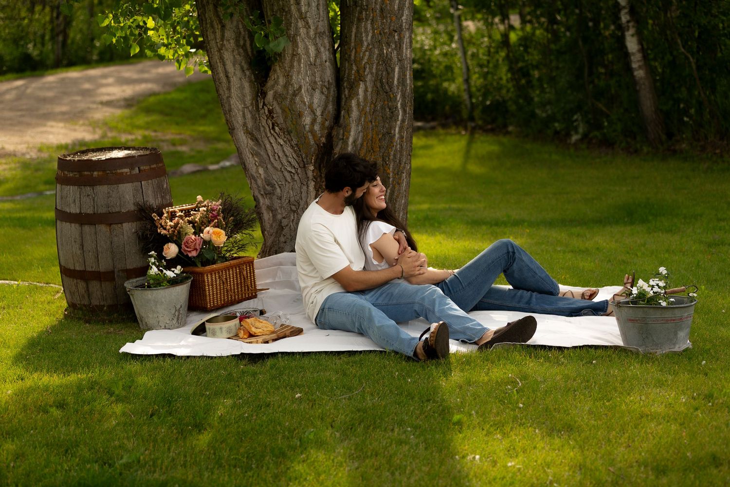 A romantic picnic setup with vintage decor and blanket under a large tree at the Lawrence House in Saskatoon, Saskatchewan.