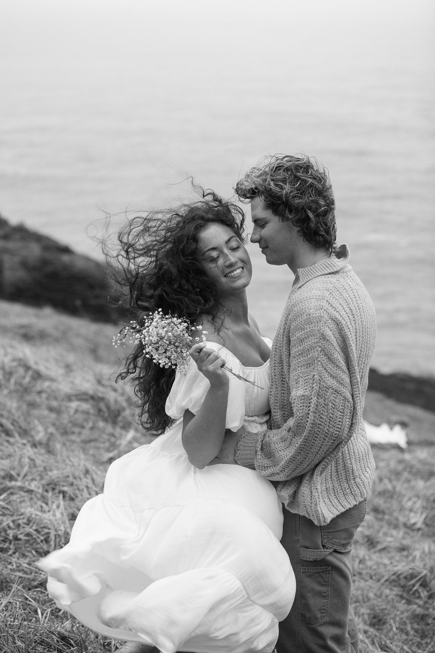 Black and white photos of a couple dancing on a windswept coastal cliff.