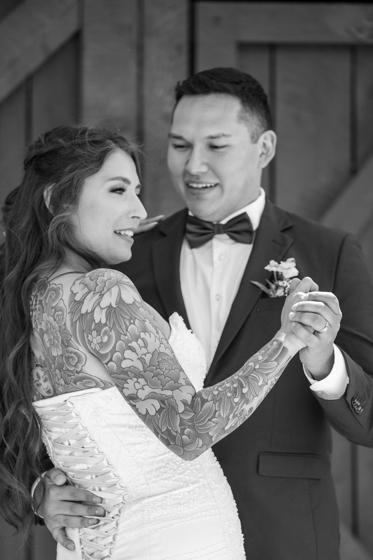 A romantic wedding couple shares a tender moment in black and white photography.