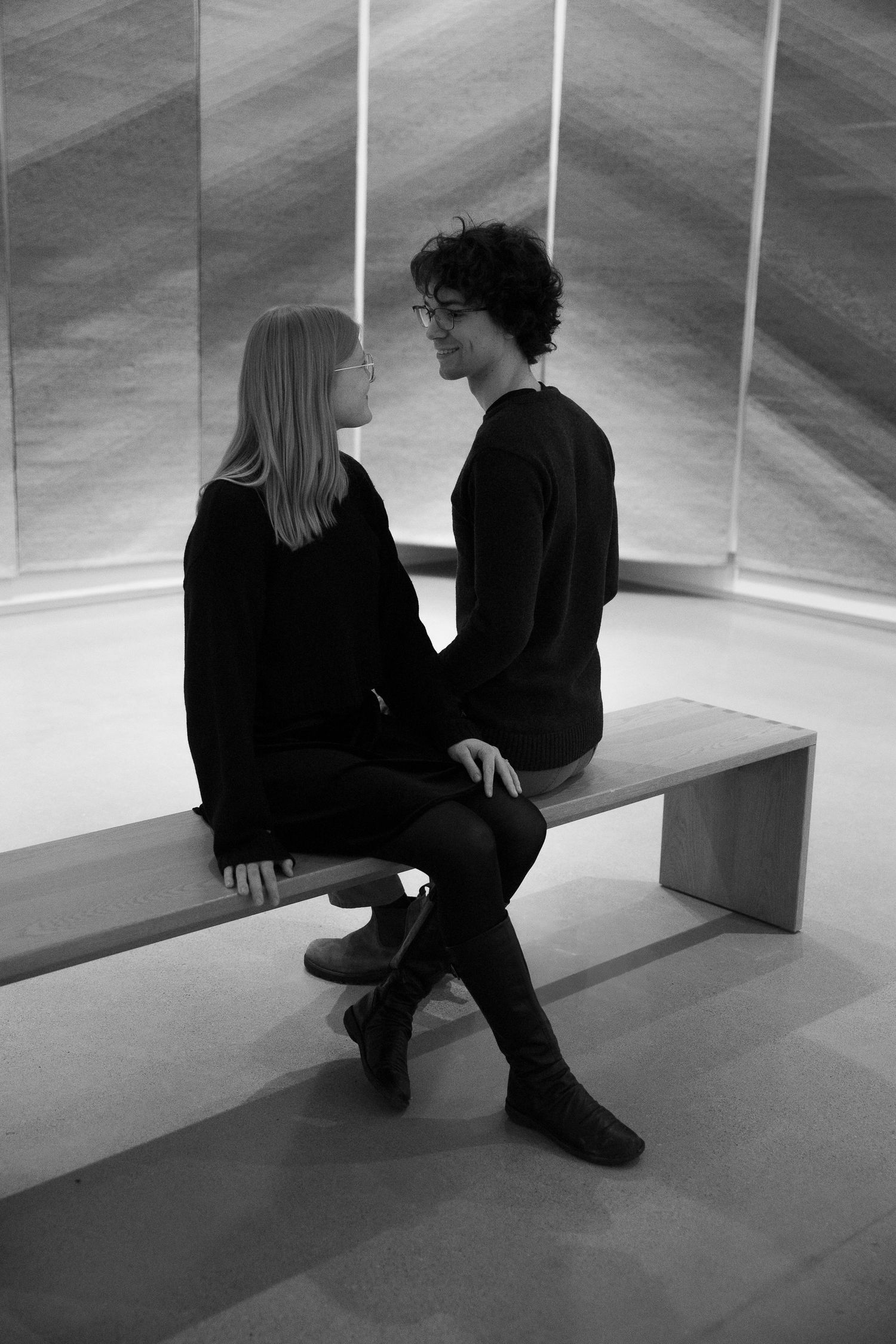 Black and white series showing two people sitting and conversing on minimalist benches at the Remai Art Gallery in Saskatoon, Saskatchewan.