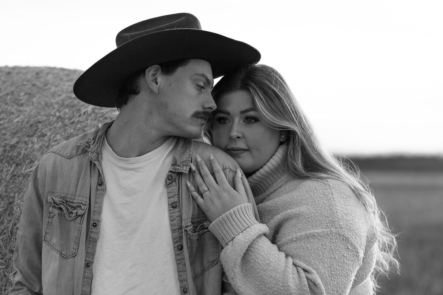 Black and white portrait of a couple embracing in western attire.